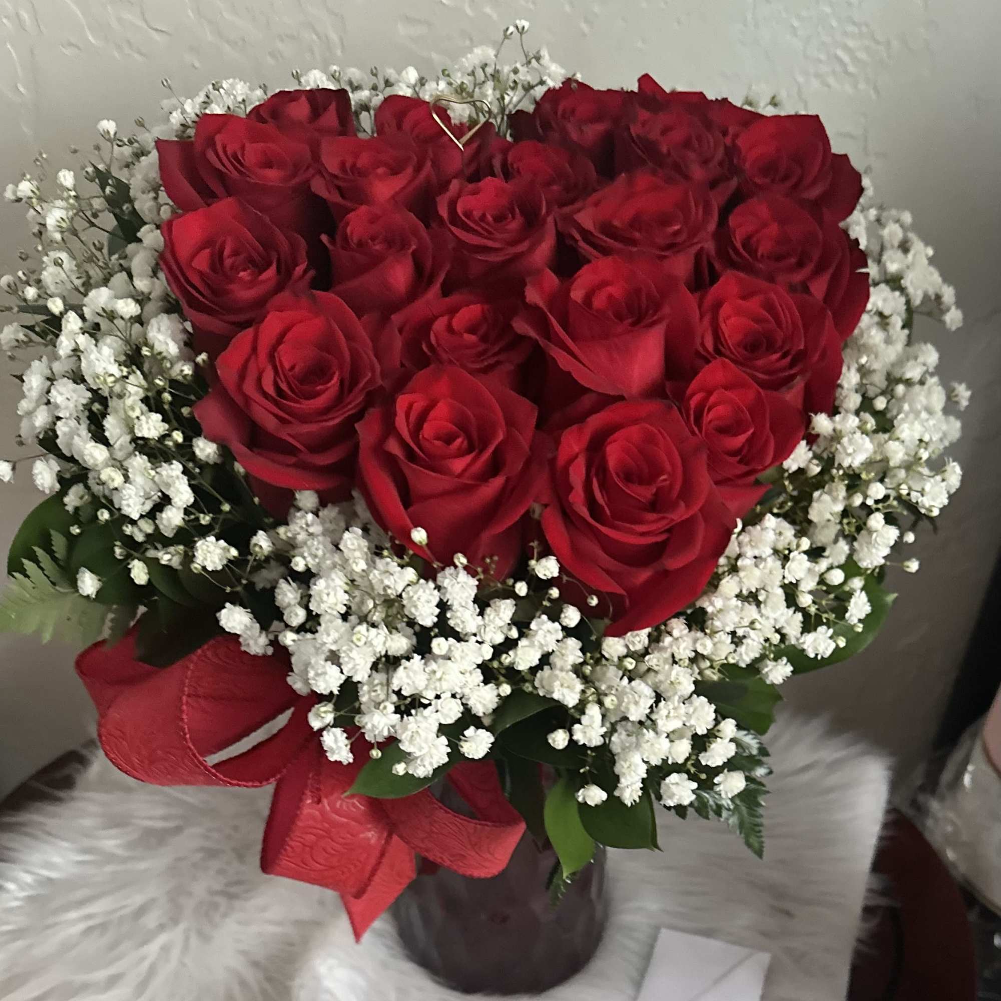Heart-shaped bouquet of red roses with white baby's breath in a vase