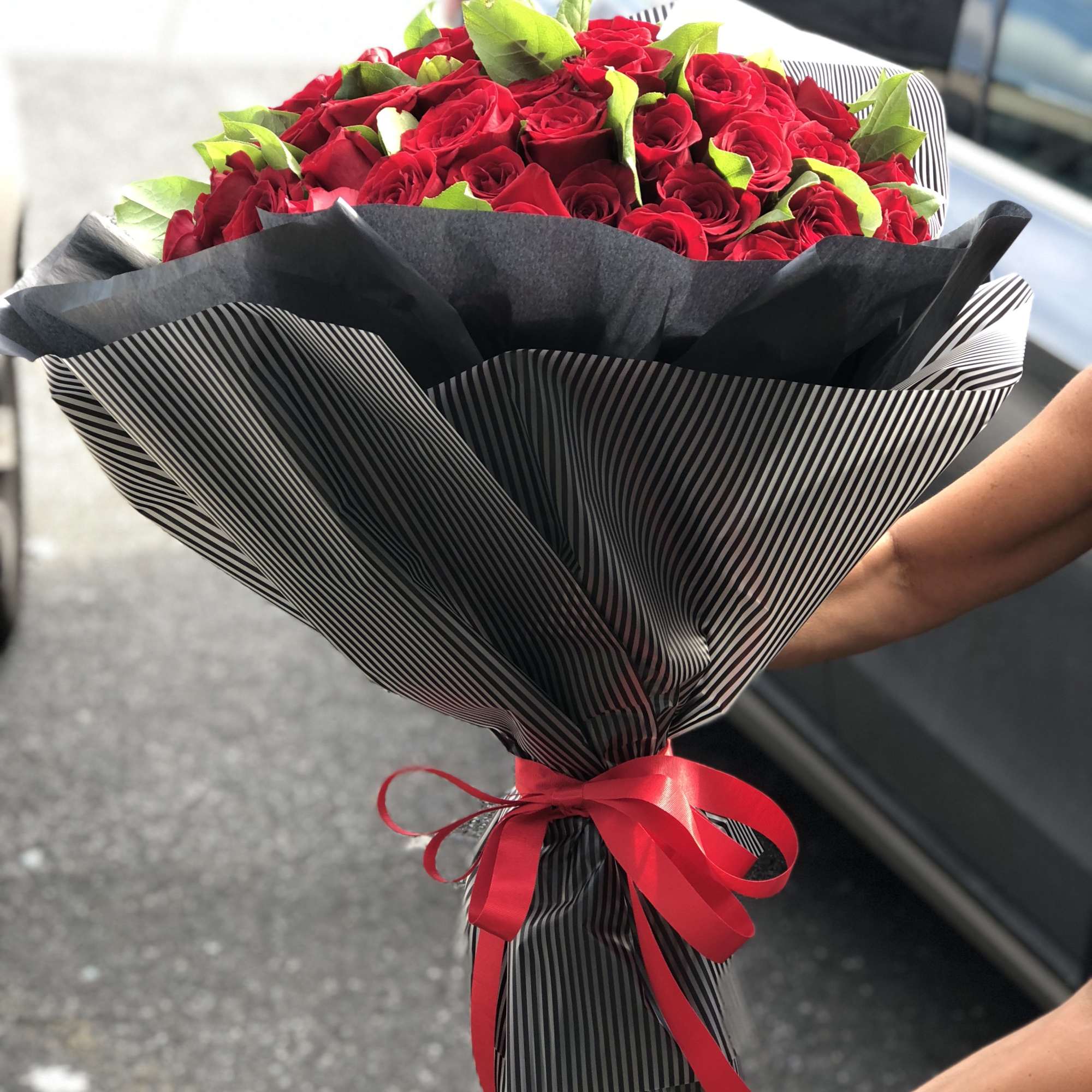 Bouquet of red roses wrapped in black striped paper with a red ribbon