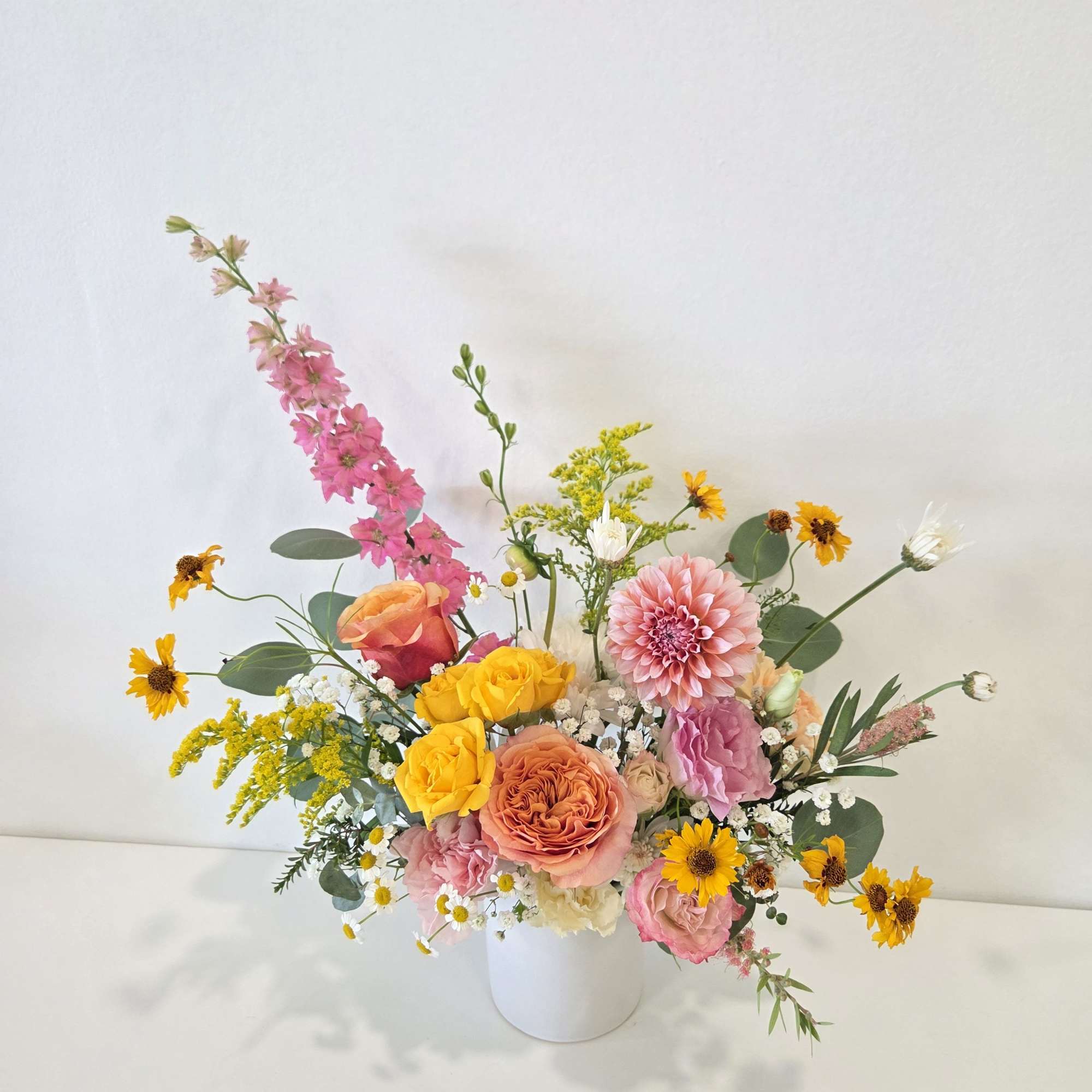 Mixed bouquet in a white vase with pink, yellow, and peach flowers