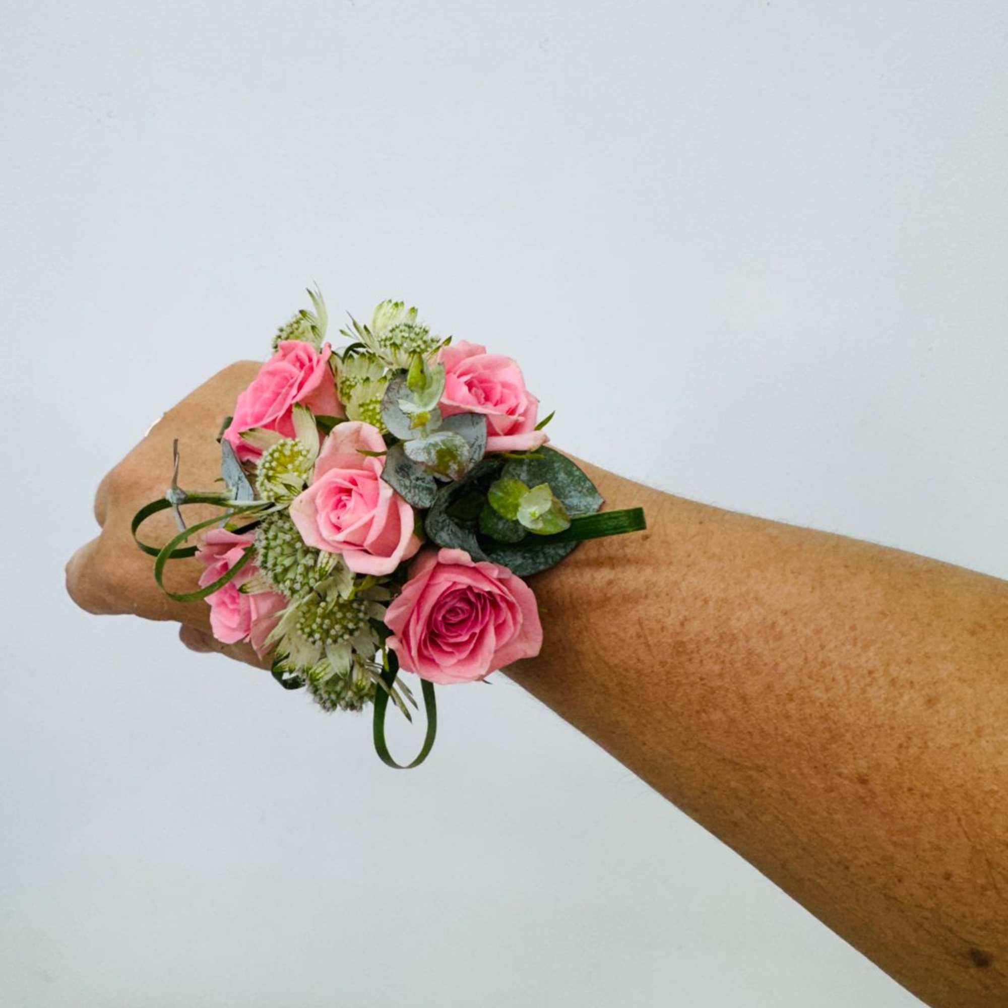 A classic  pink rose and baby's breath corsage compliments any outfit.
