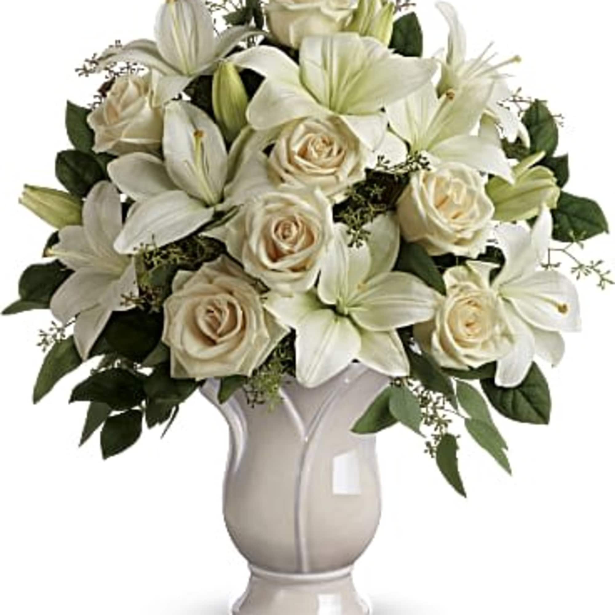 White lilies and cream roses arranged in a ceramic vase