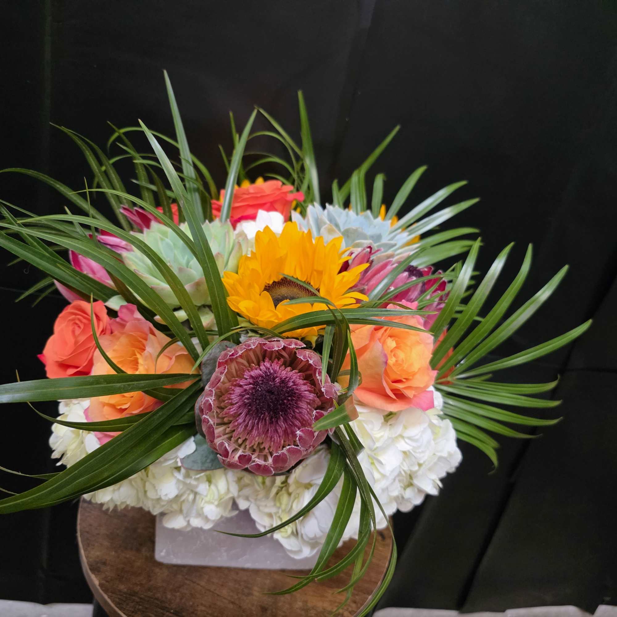 A bright sunflower center and coral-pink roses make this mixed-color bouquet a