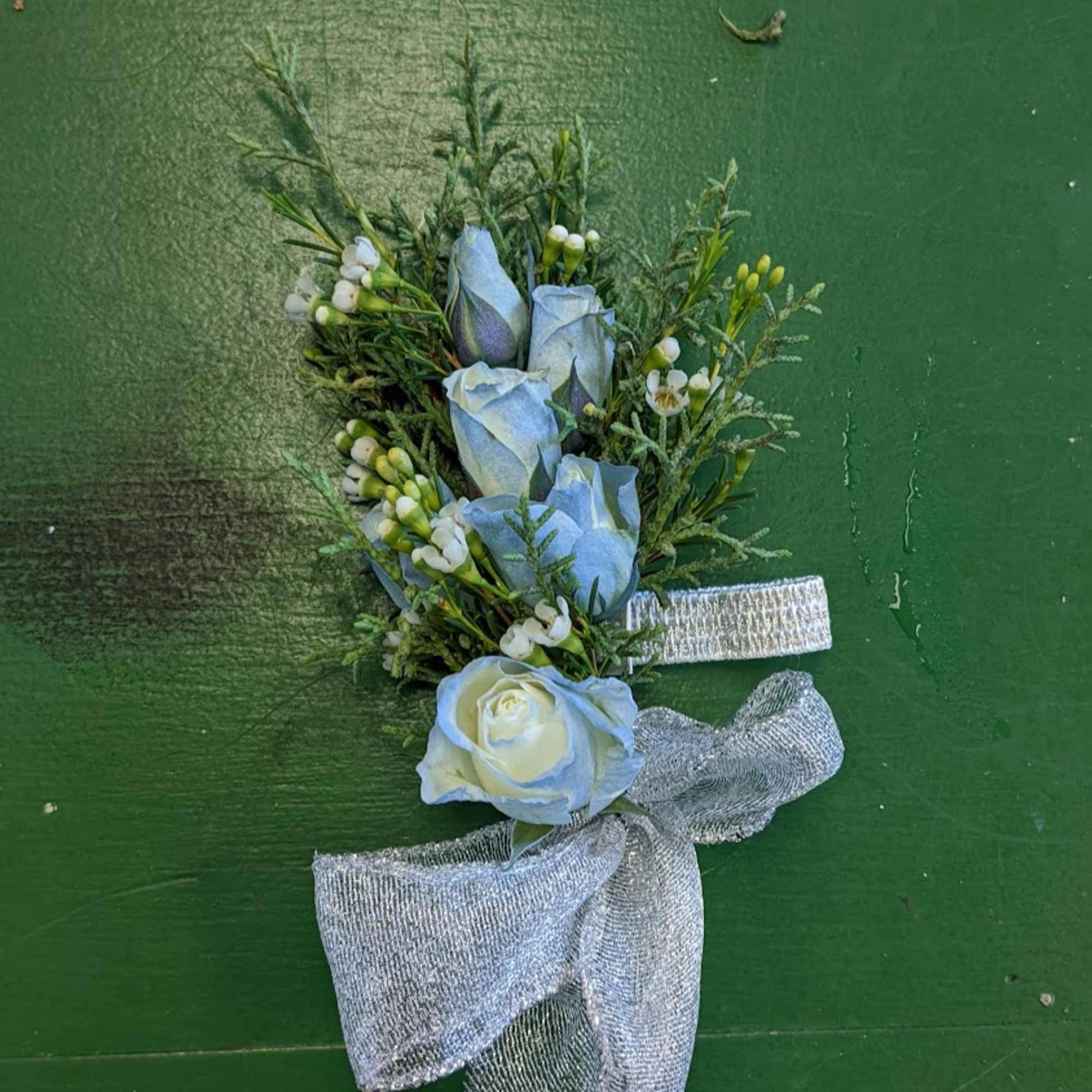 Blue-tinted rose boutonniere with white filler flowers and silver ribbon