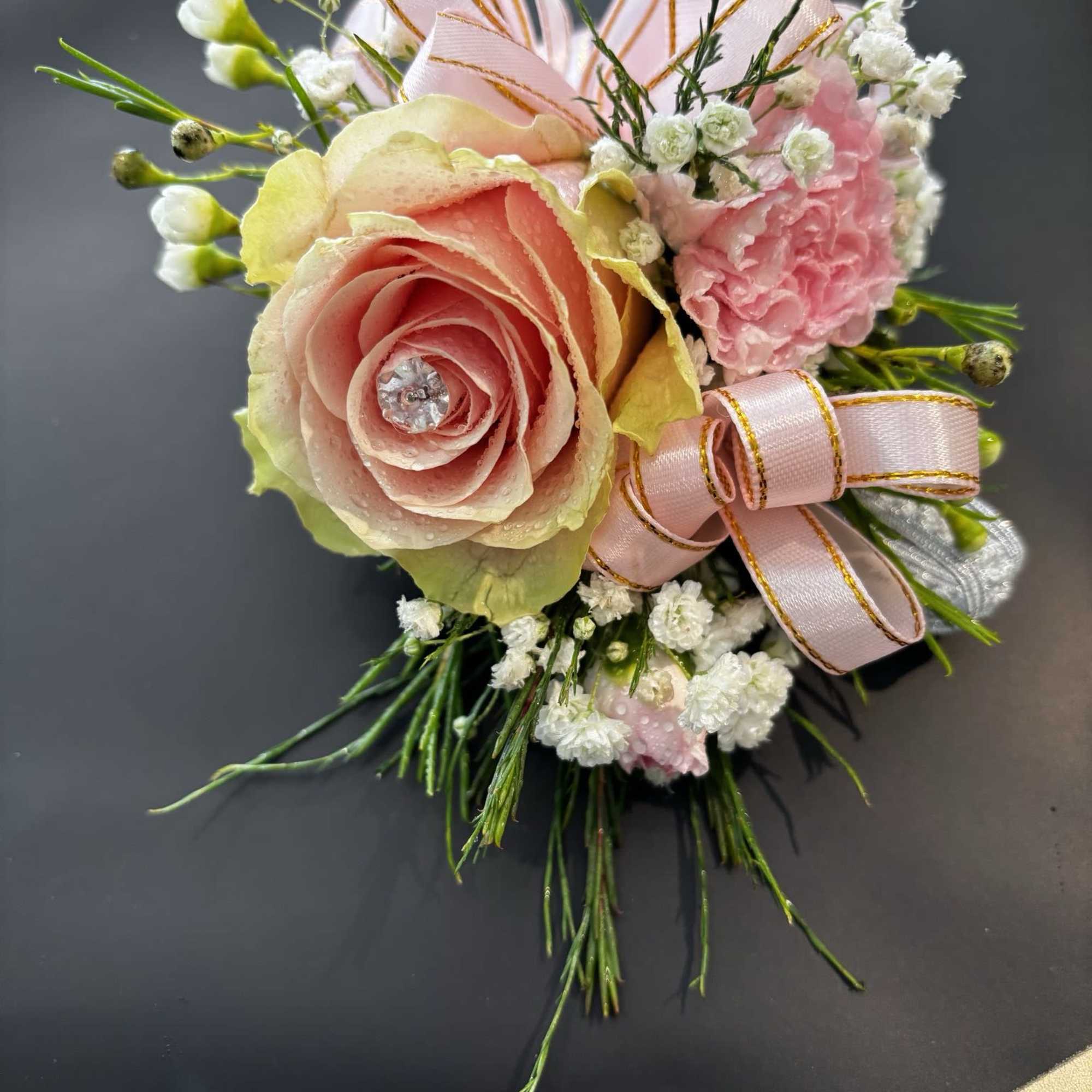 Pink rose boutonniere with baby's breath and ribbon