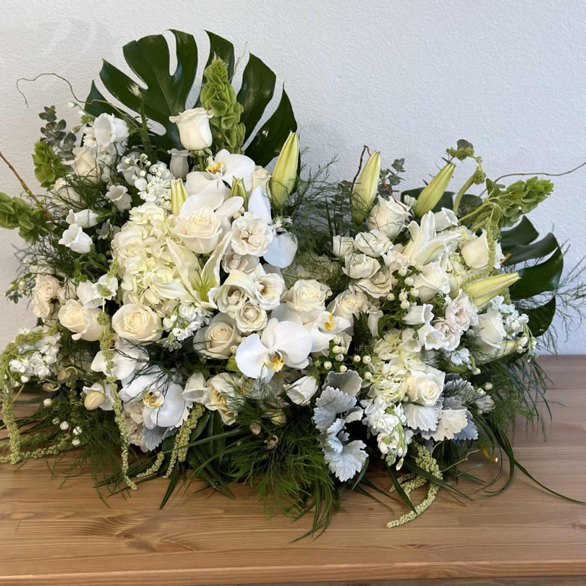 Large white floral arrangement with orchids, roses, and lilies