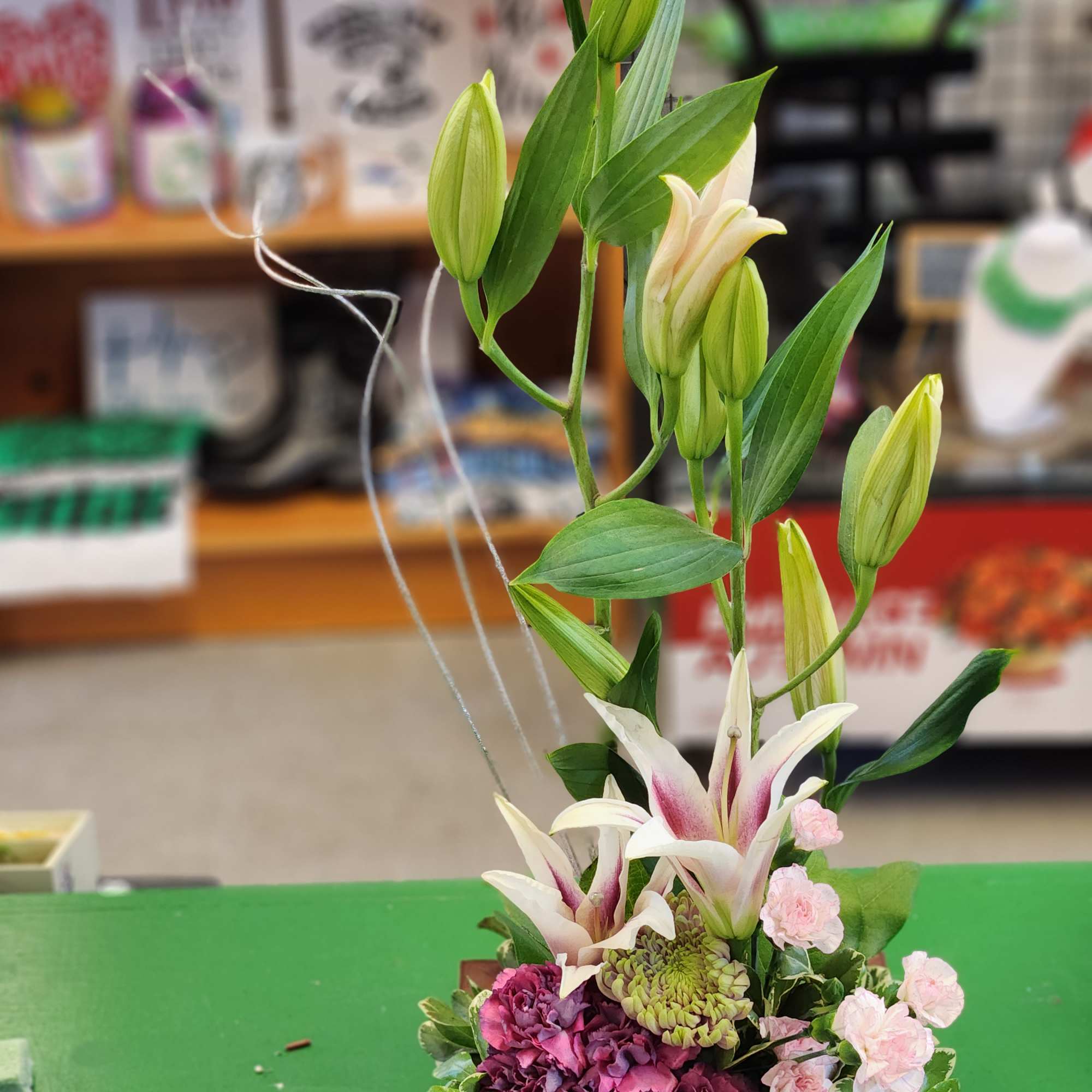 Tall floral arrangement with lilies and pink blooms in a wooden base