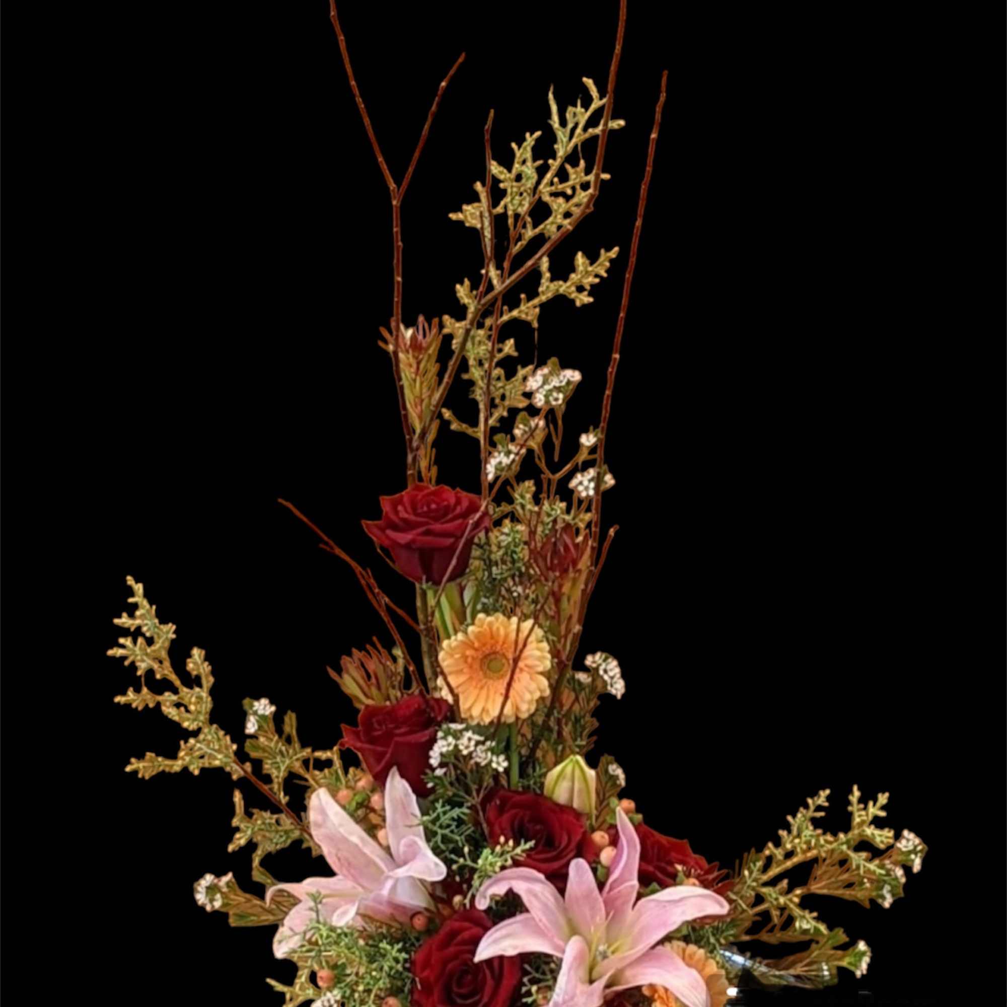 Tall floral arrangement with red roses, pink lilies, and peach daisies