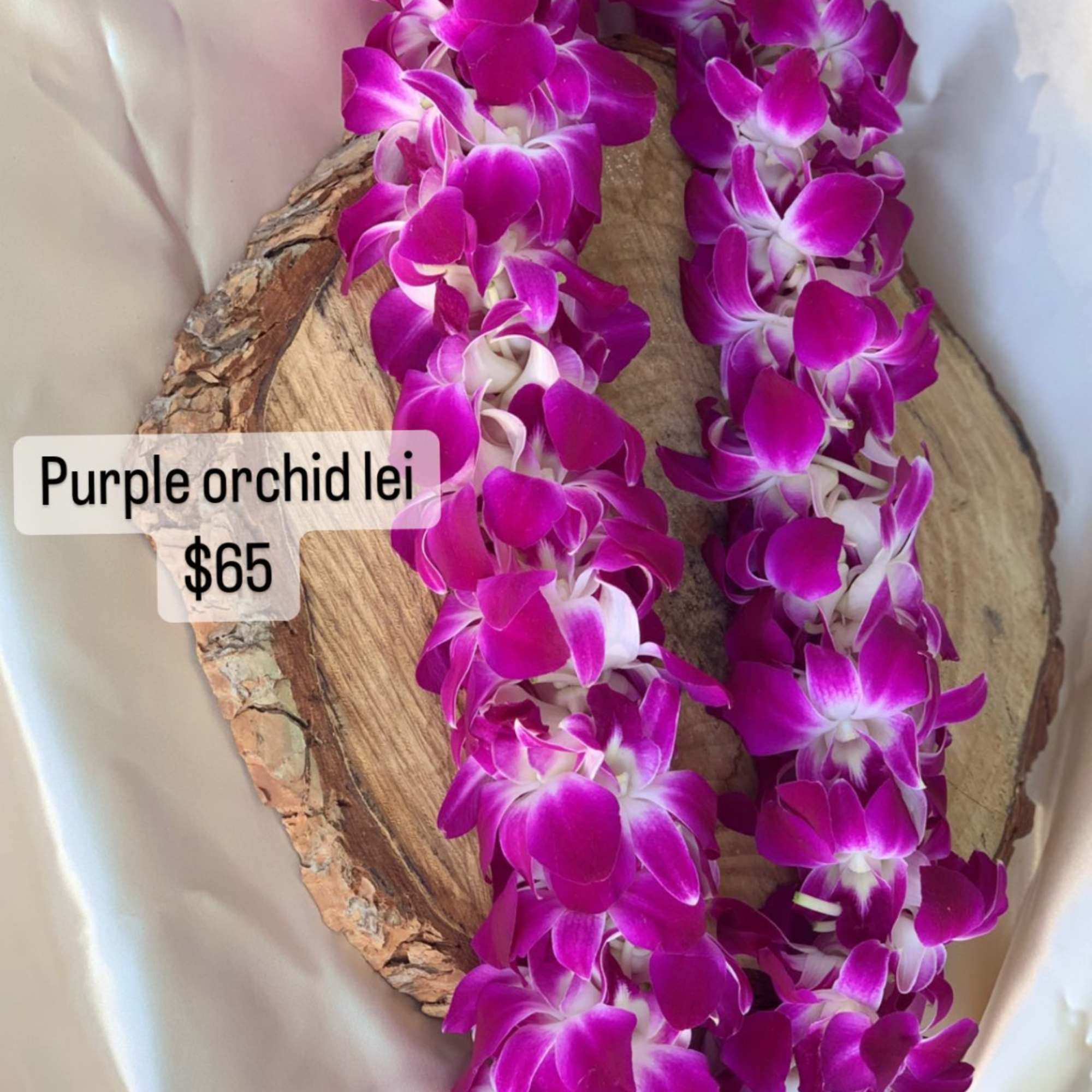 Purple orchid lei draped over a wood slice