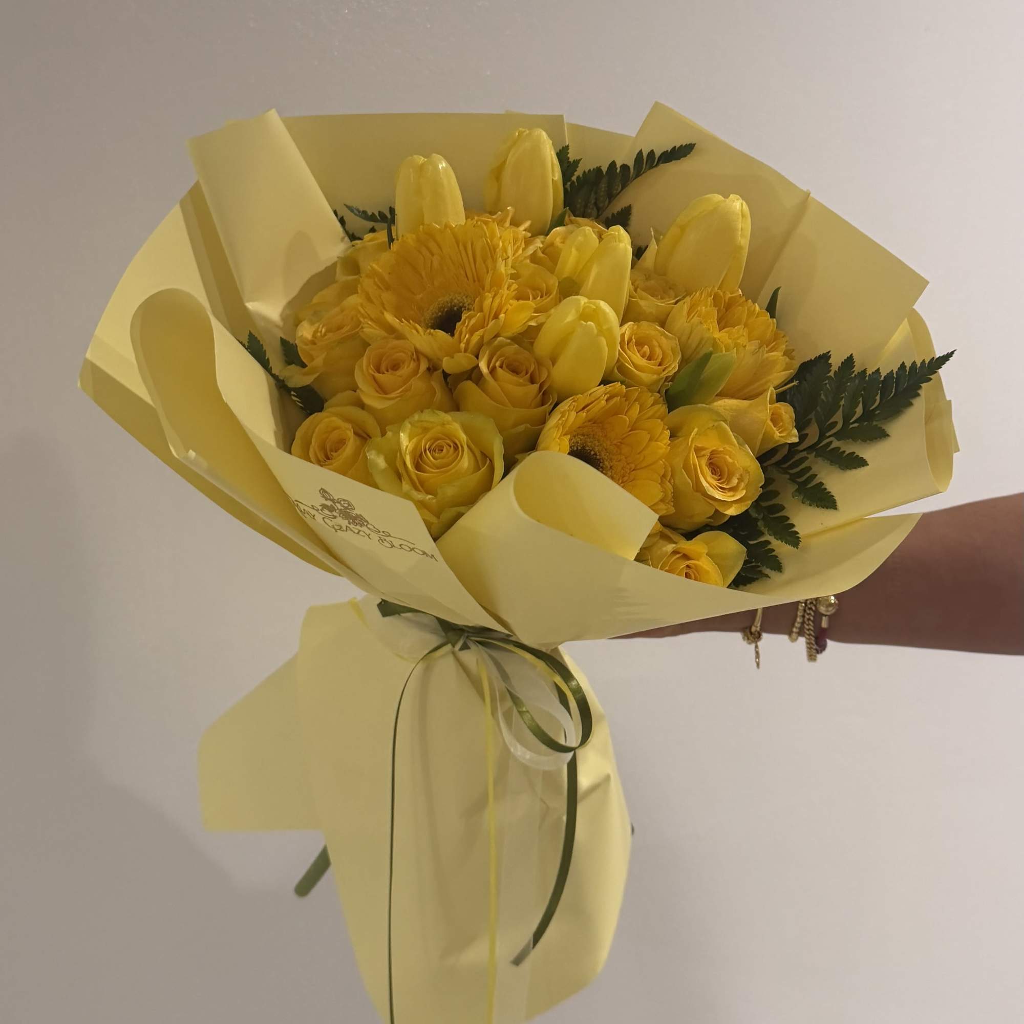 Sunny yellow roses, tulips, and gerbera daisies come together in a compact