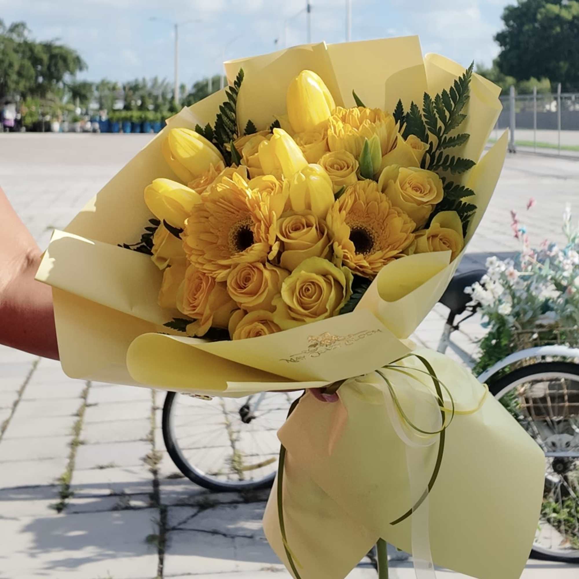 Sunny yellow roses, tulips, and gerbera daisies come together in a compact