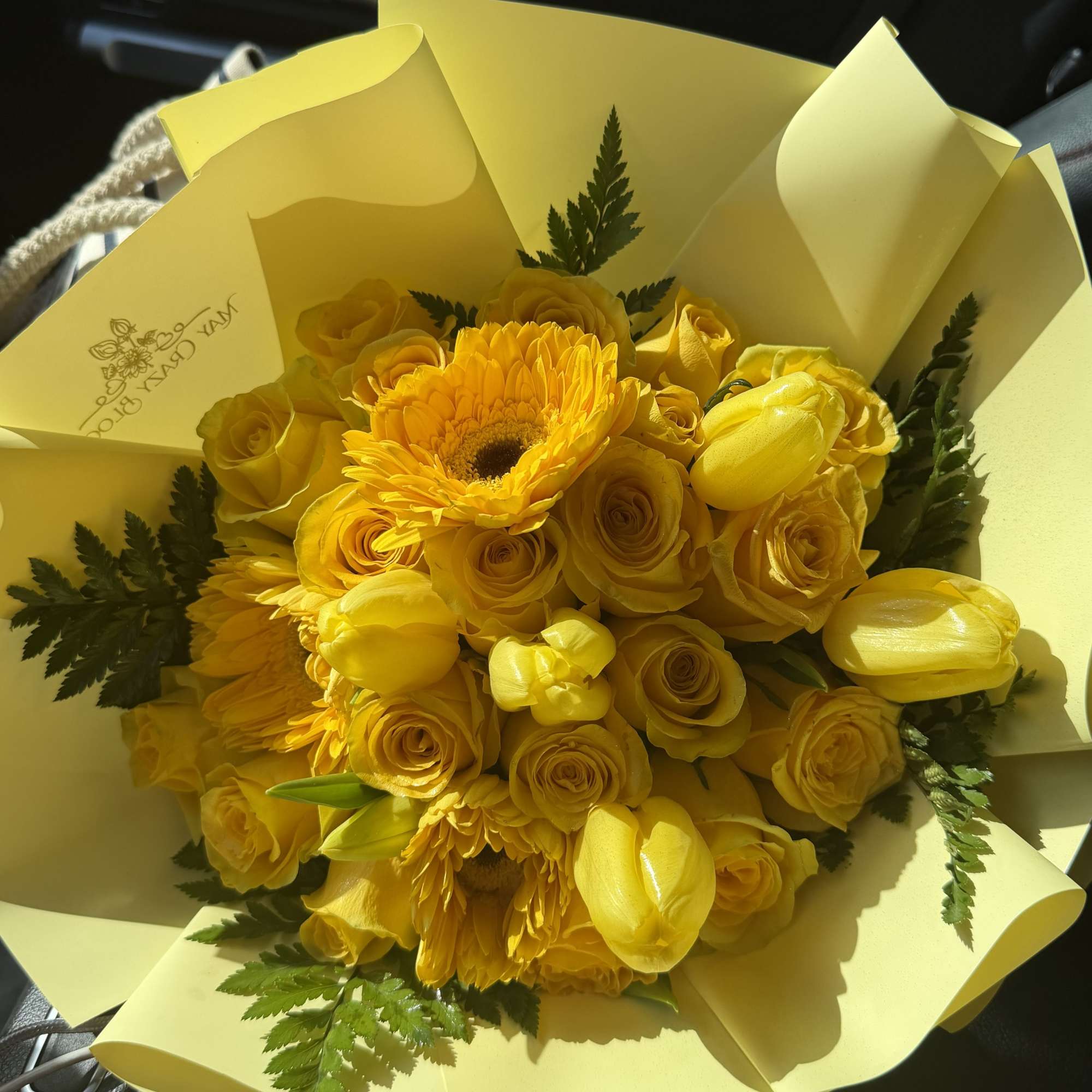 Sunny yellow roses, tulips, and gerbera daisies come together in a compact