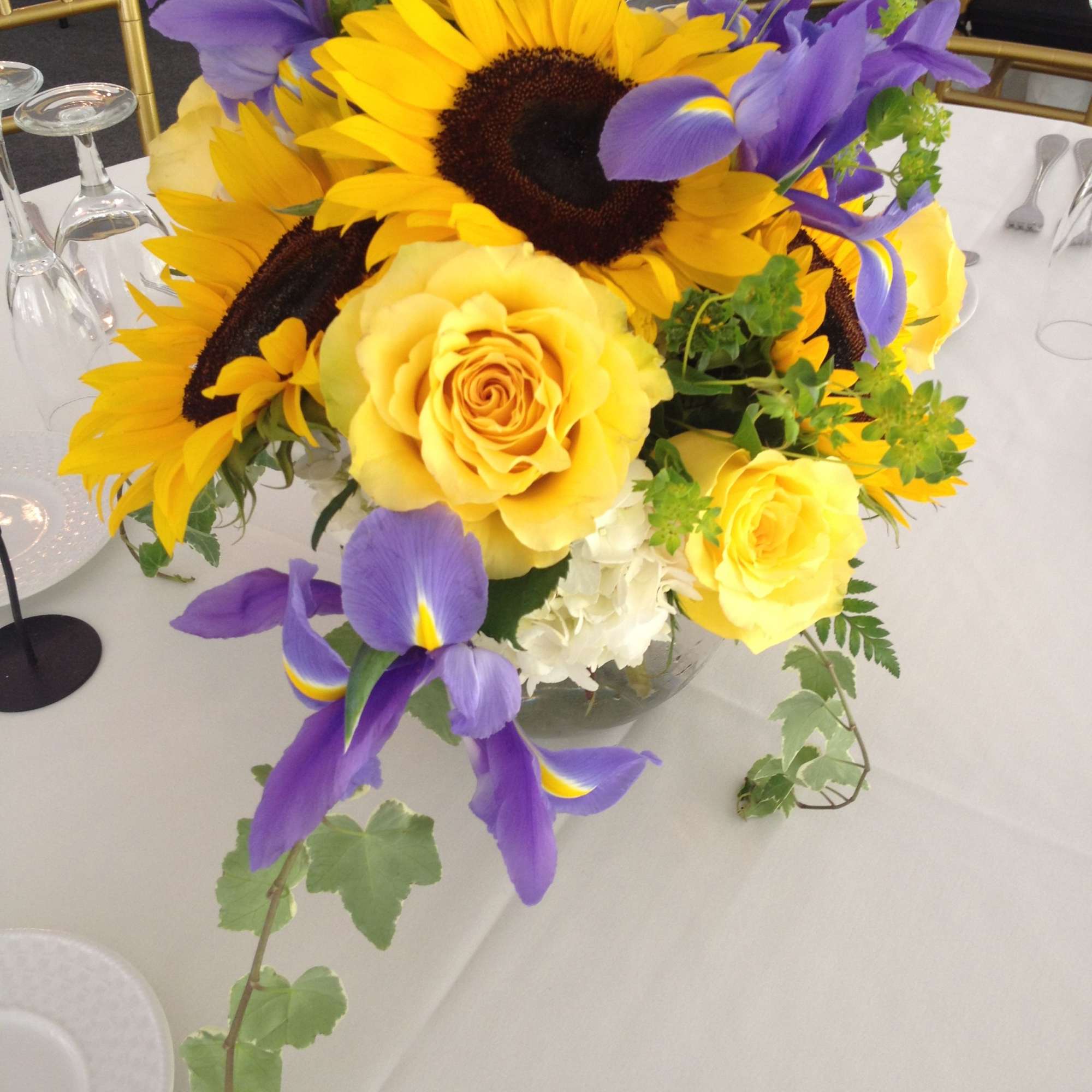 Yellow roses and sunflowers with purple irises in a glass vase