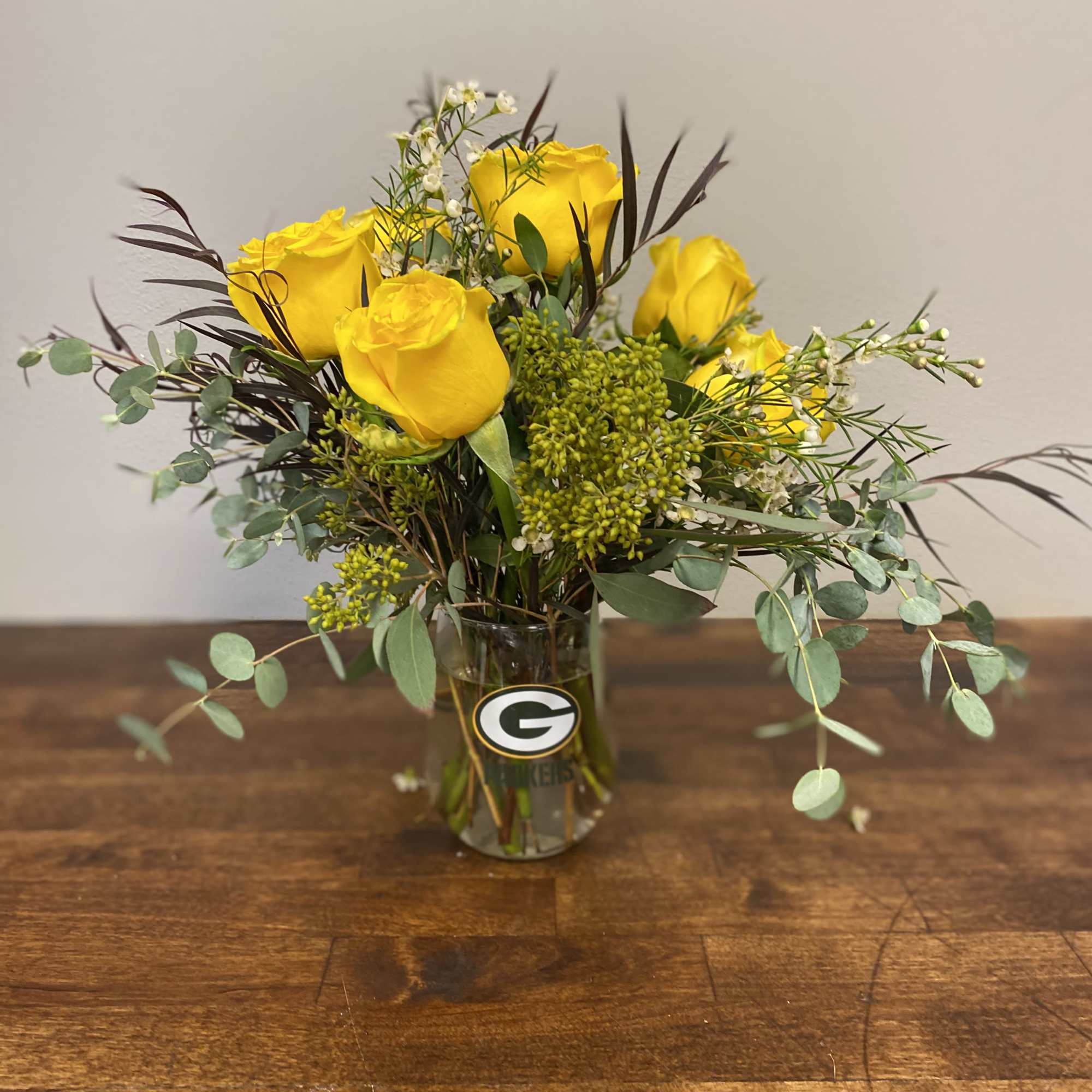 A stemless Packers Glass wineglass, filled with a combination of green and
