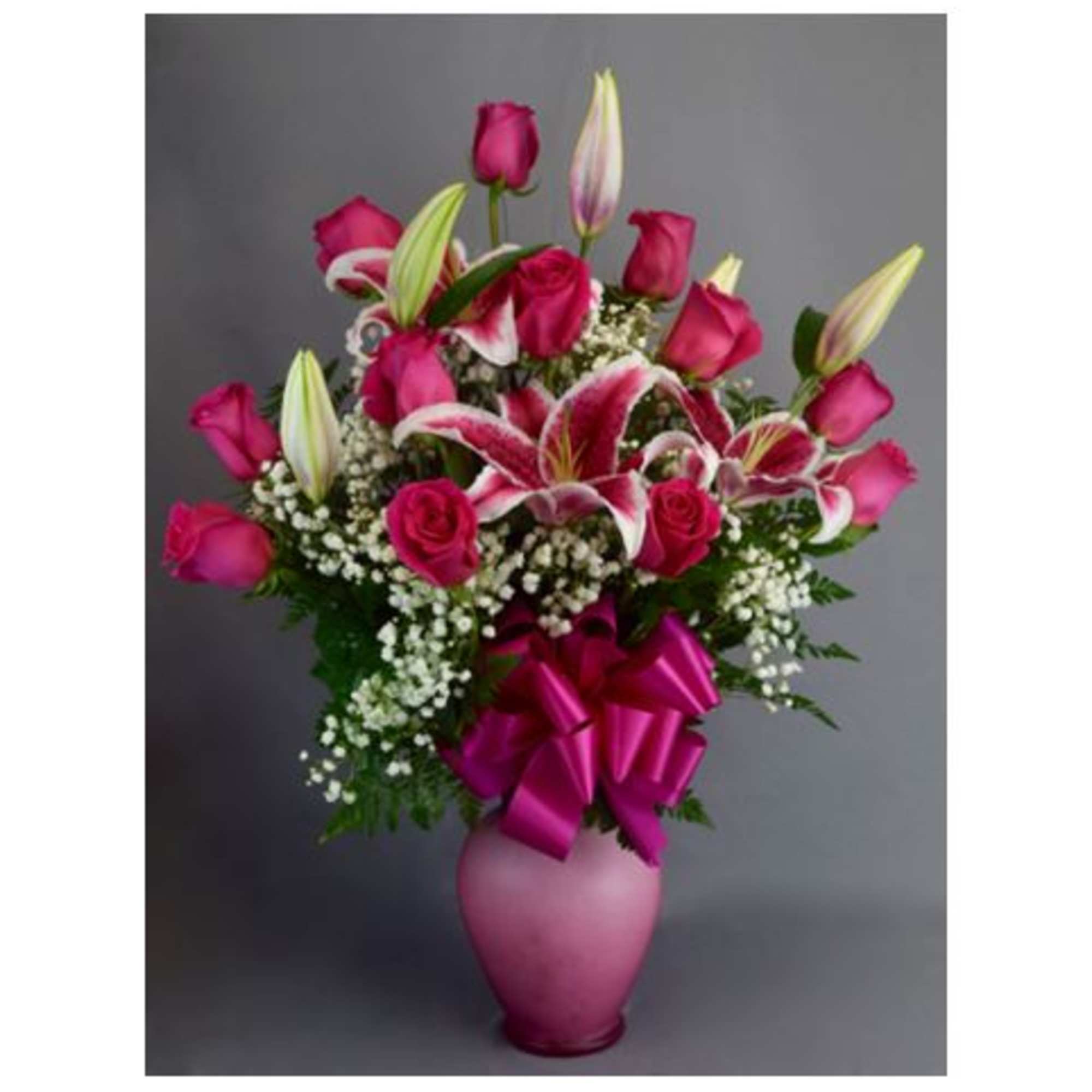Pink roses and lilies in a pink vase with a ribbon
