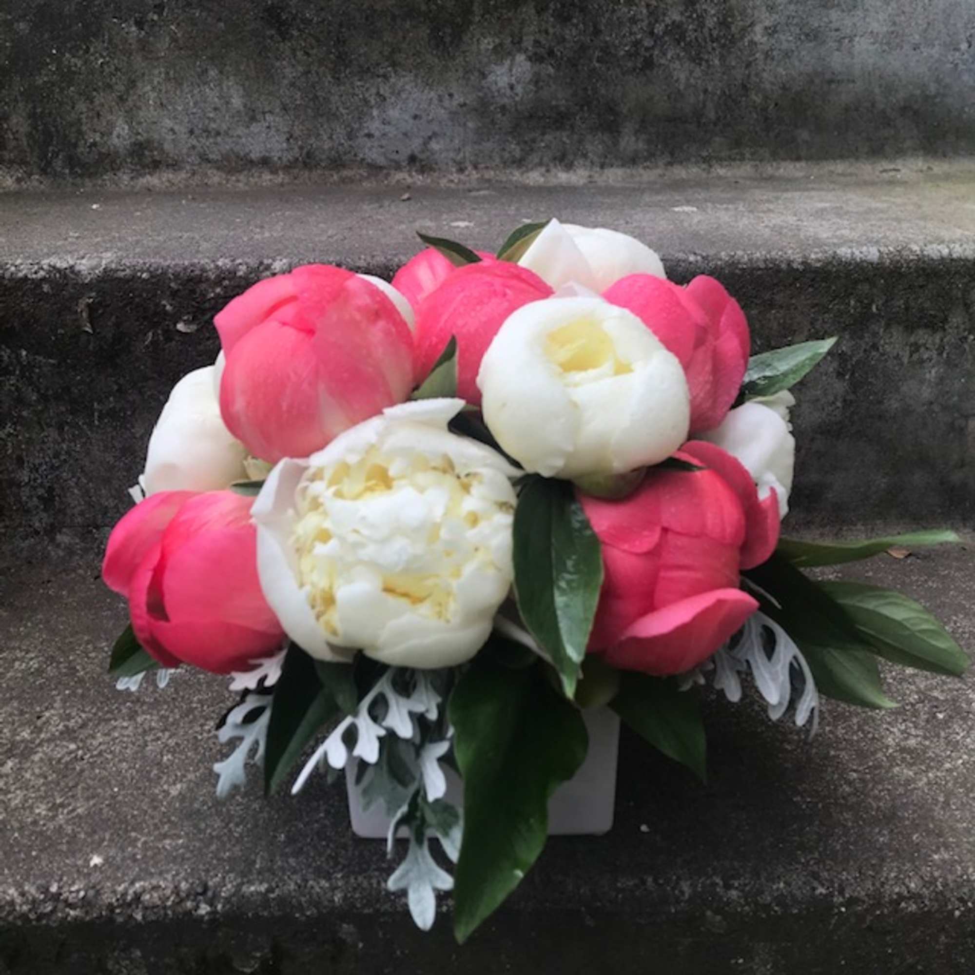 Pink and white peony bouquet in a white container