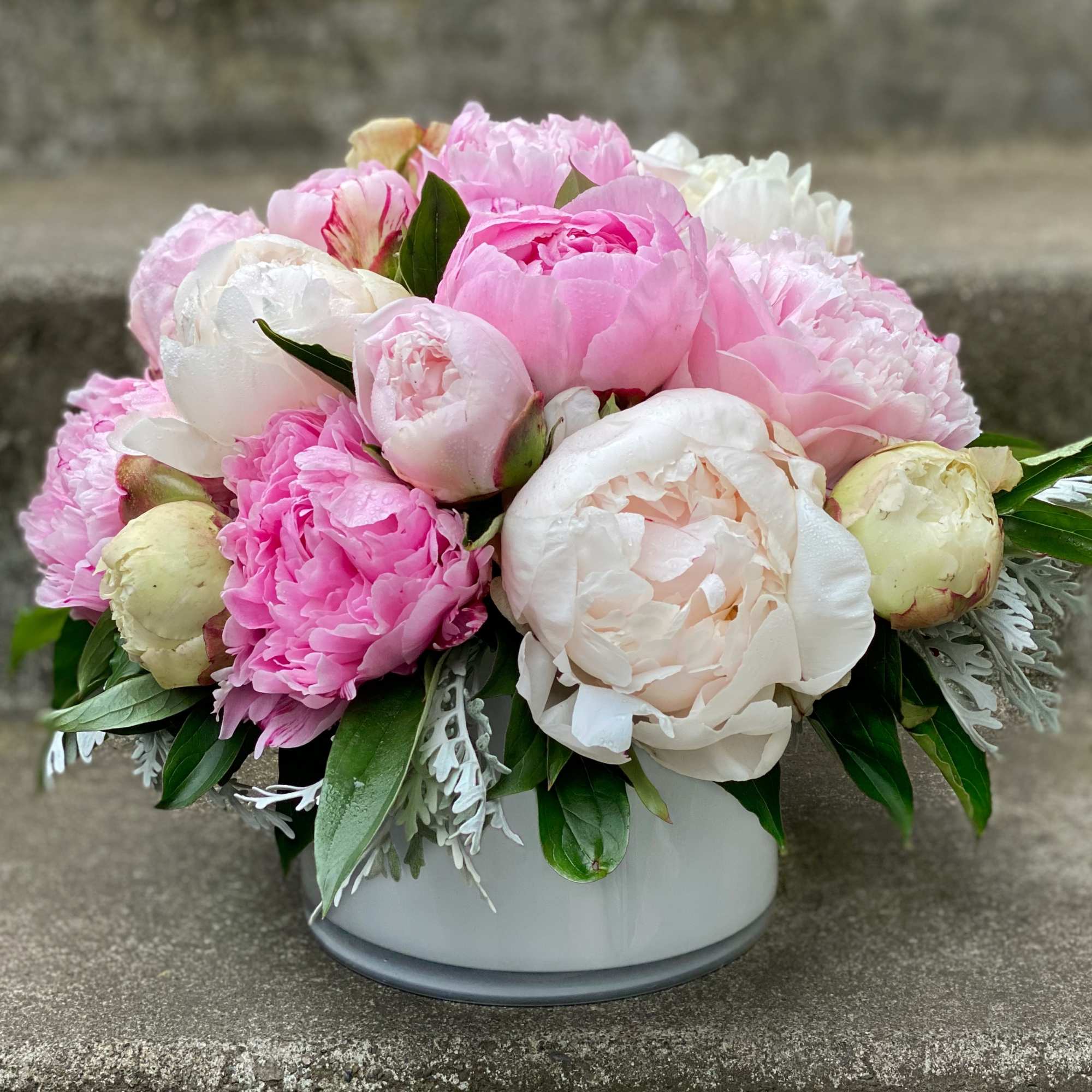 Pink and white peony bouquet in a low white vase