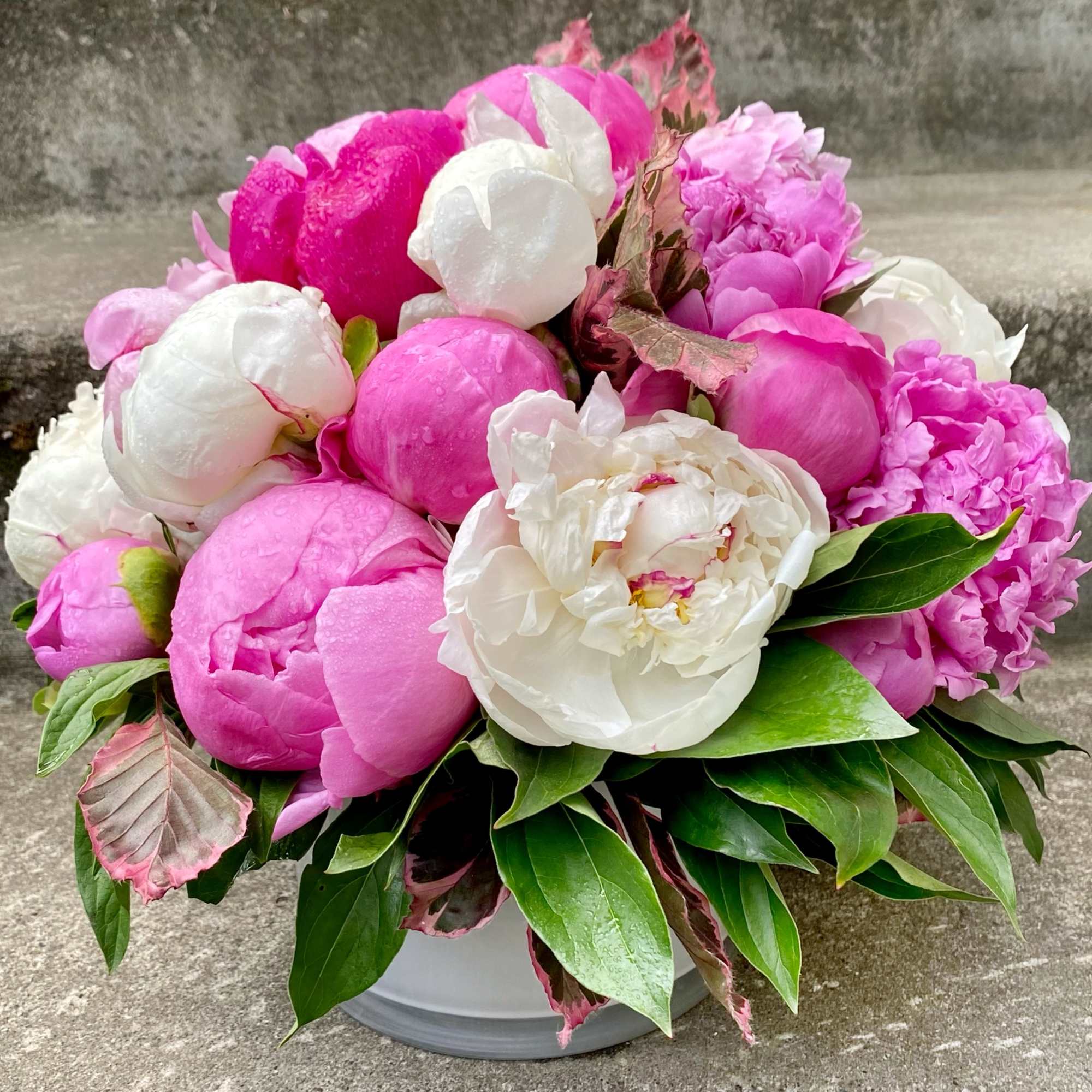 Pink and white peony bouquet in a low white container