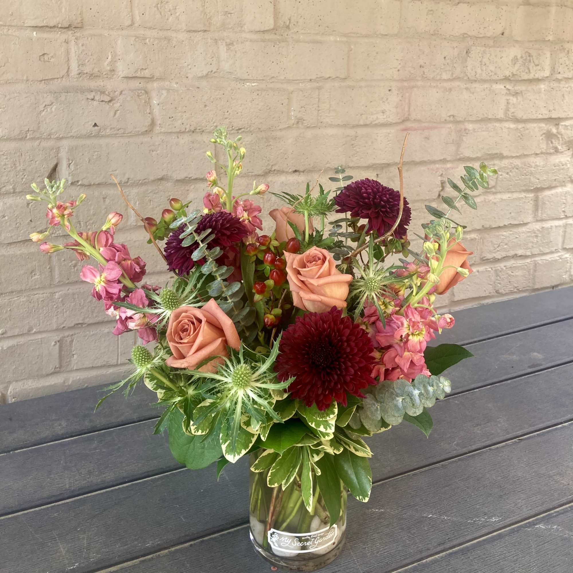 Toffee colored roses paired with deep burgundy chrysanthemums give this flower arrangement