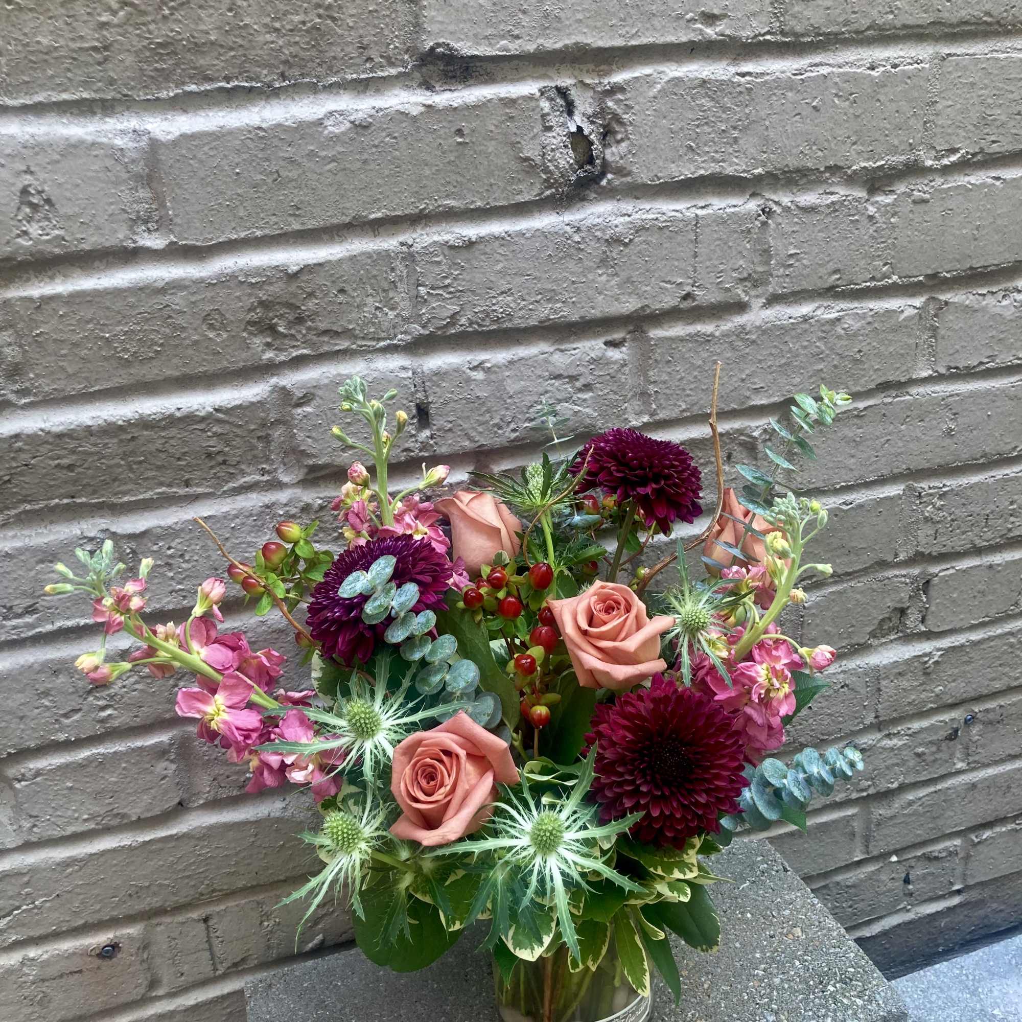 Toffee colored roses paired with deep burgundy chrysanthemums give this flower arrangement