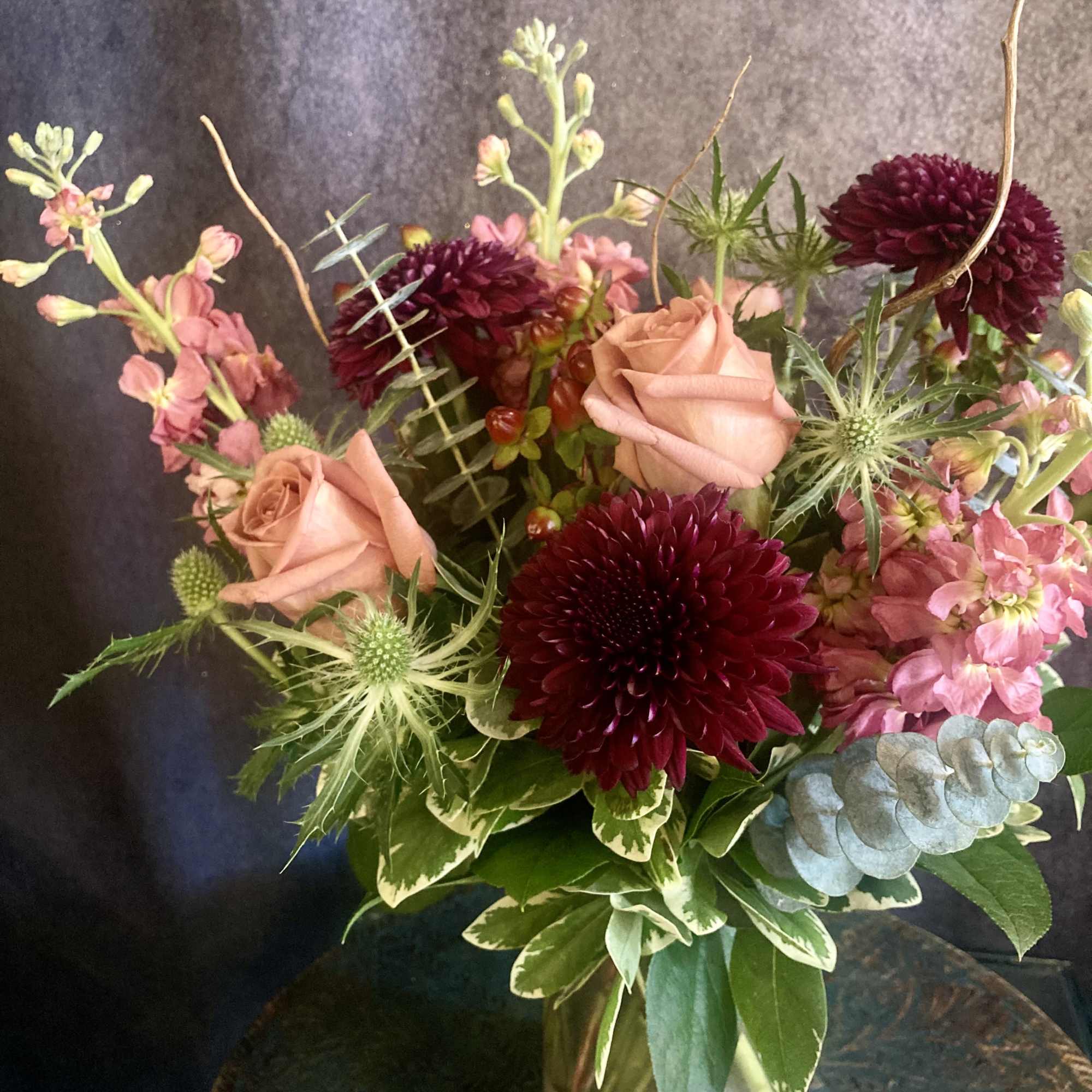 Toffee colored roses paired with deep burgundy chrysanthemums give this flower arrangement