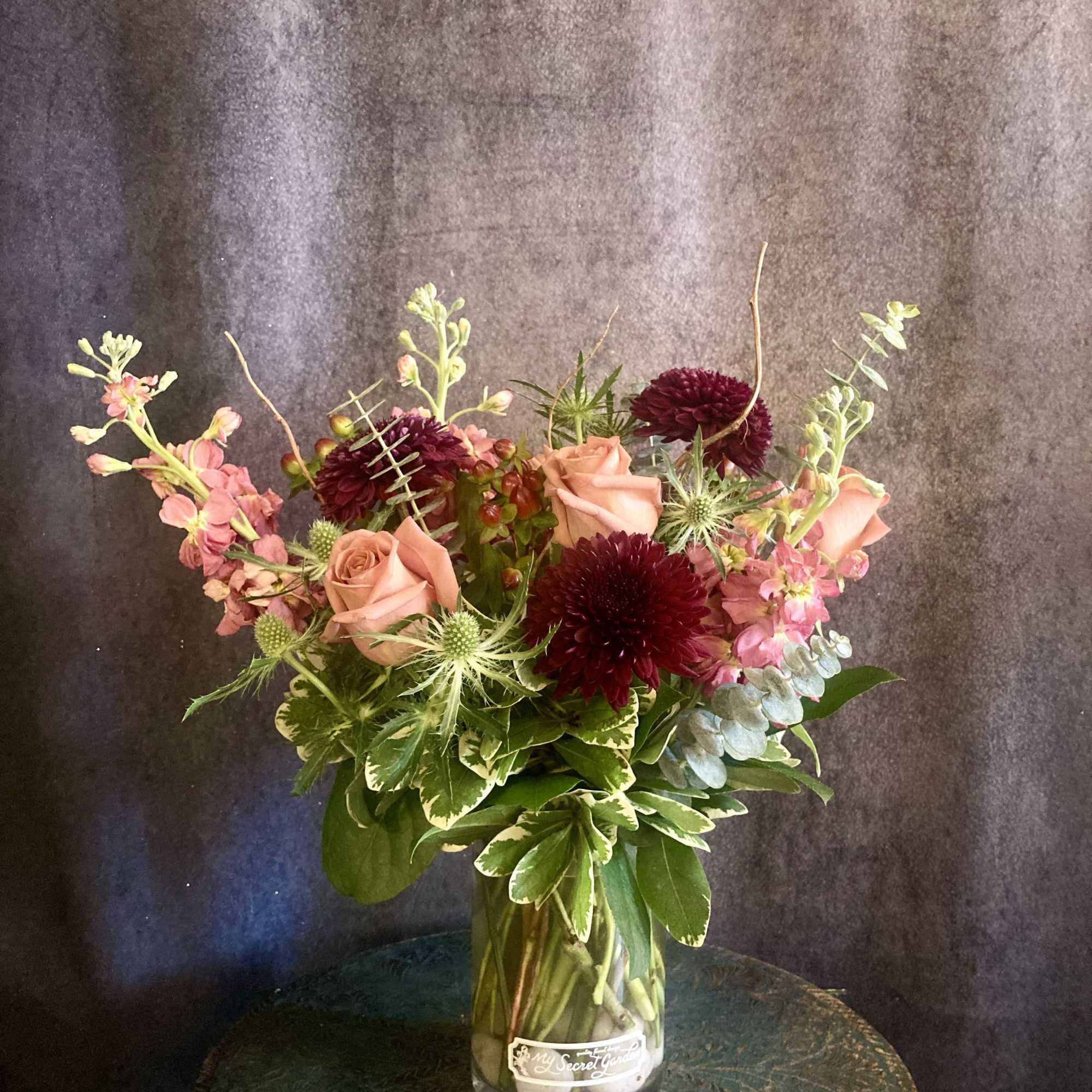 Toffee colored roses paired with deep burgundy chrysanthemums give this flower arrangement