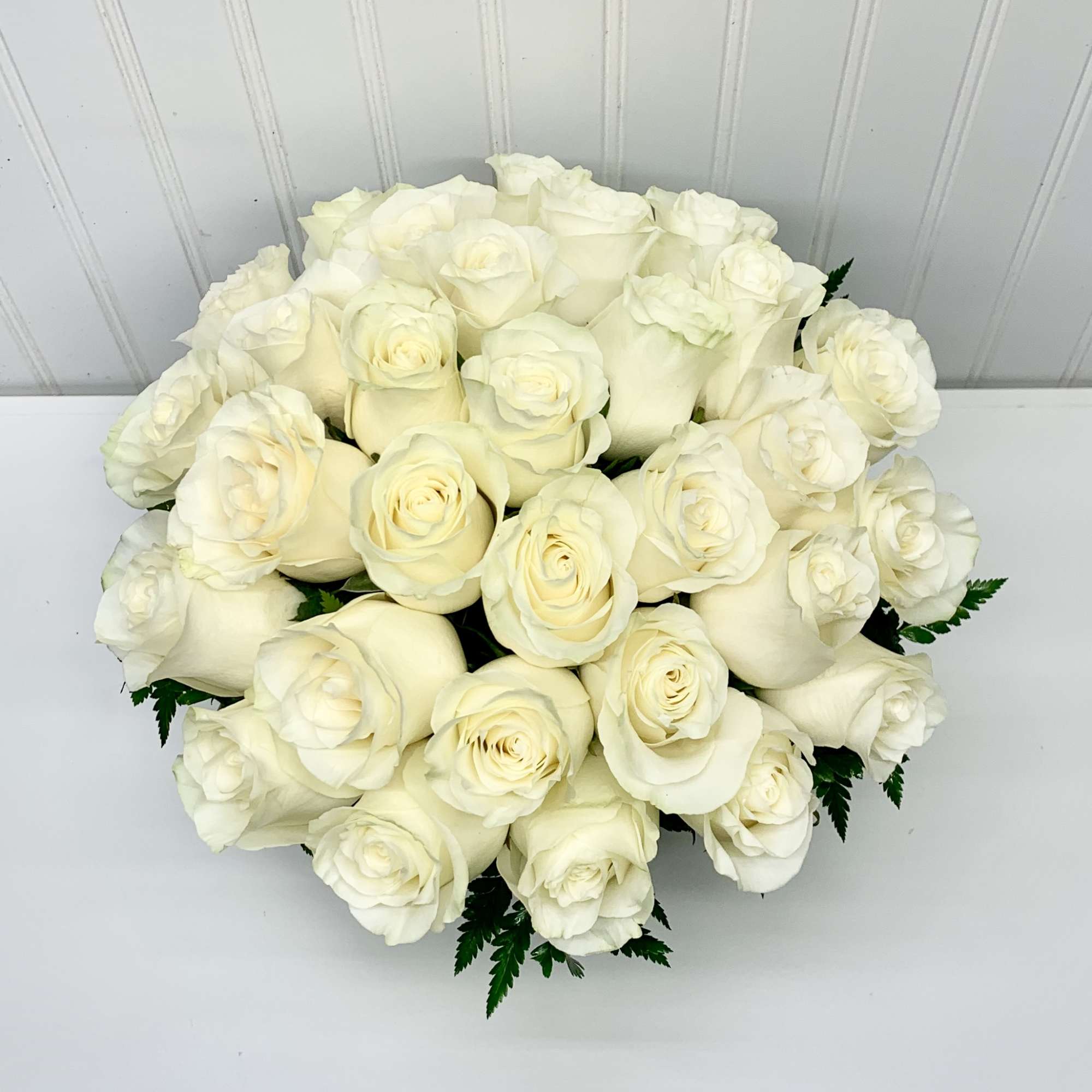 Low round arrangement of tightly clustered ivory roses viewed from above
