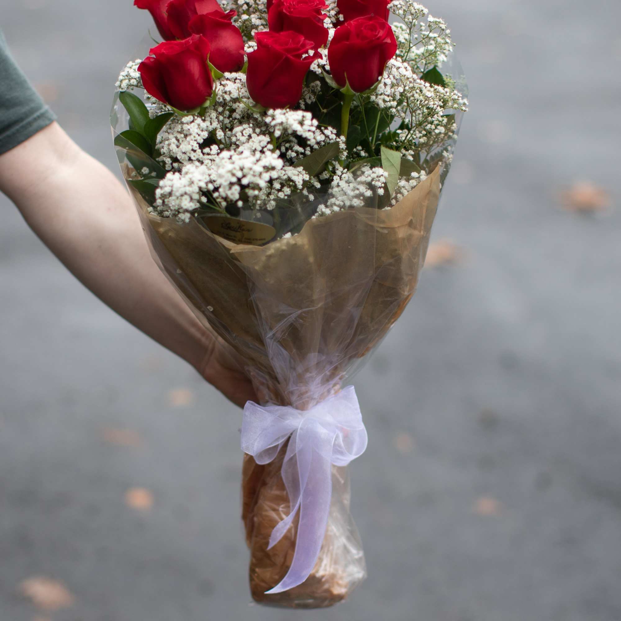 Bouquet of red roses with white baby's breath wrapped in brown paper and ribbon