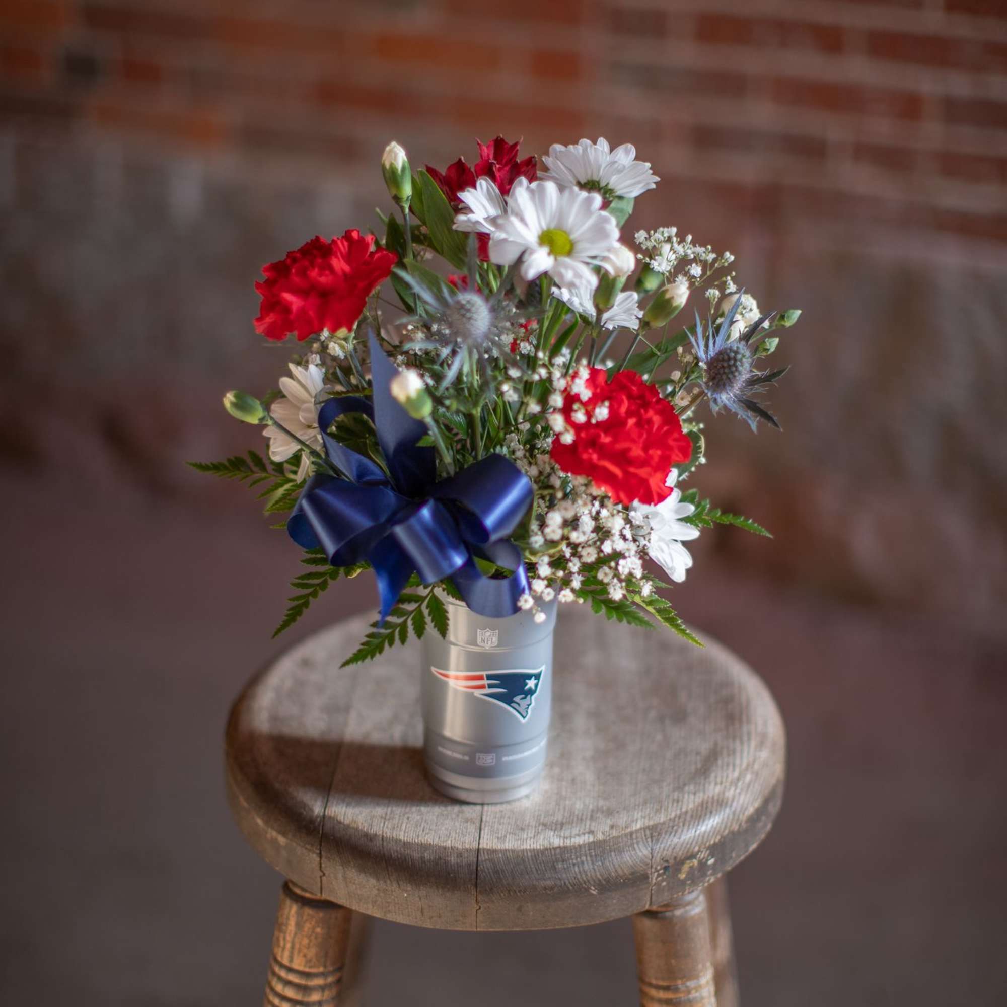 Bouquet of red and white flowers in a silver cup with a blue ribbon