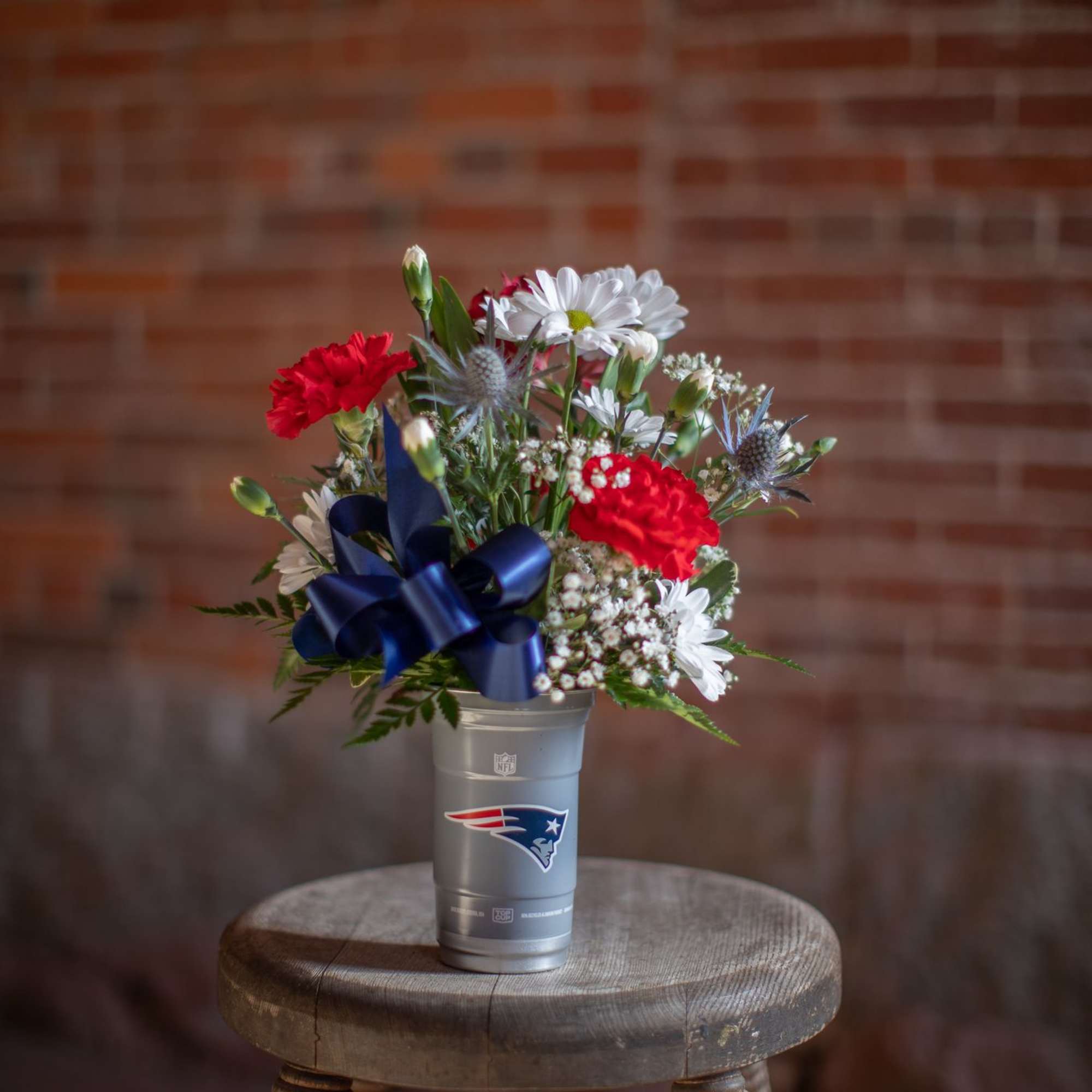 Bouquet of red and white flowers in a Patriots cup