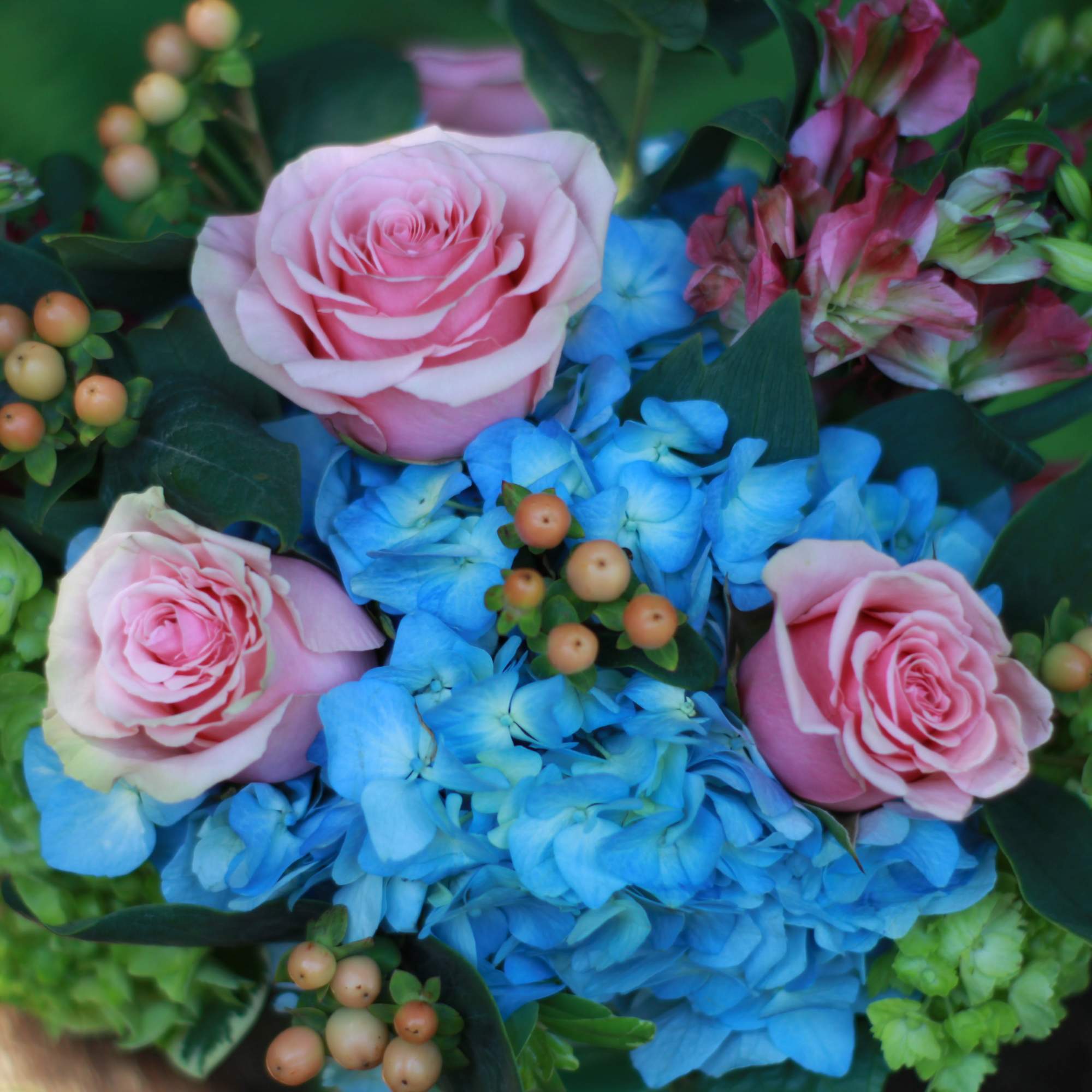 Bouquet of pink roses and blue hydrangeas with berry accents