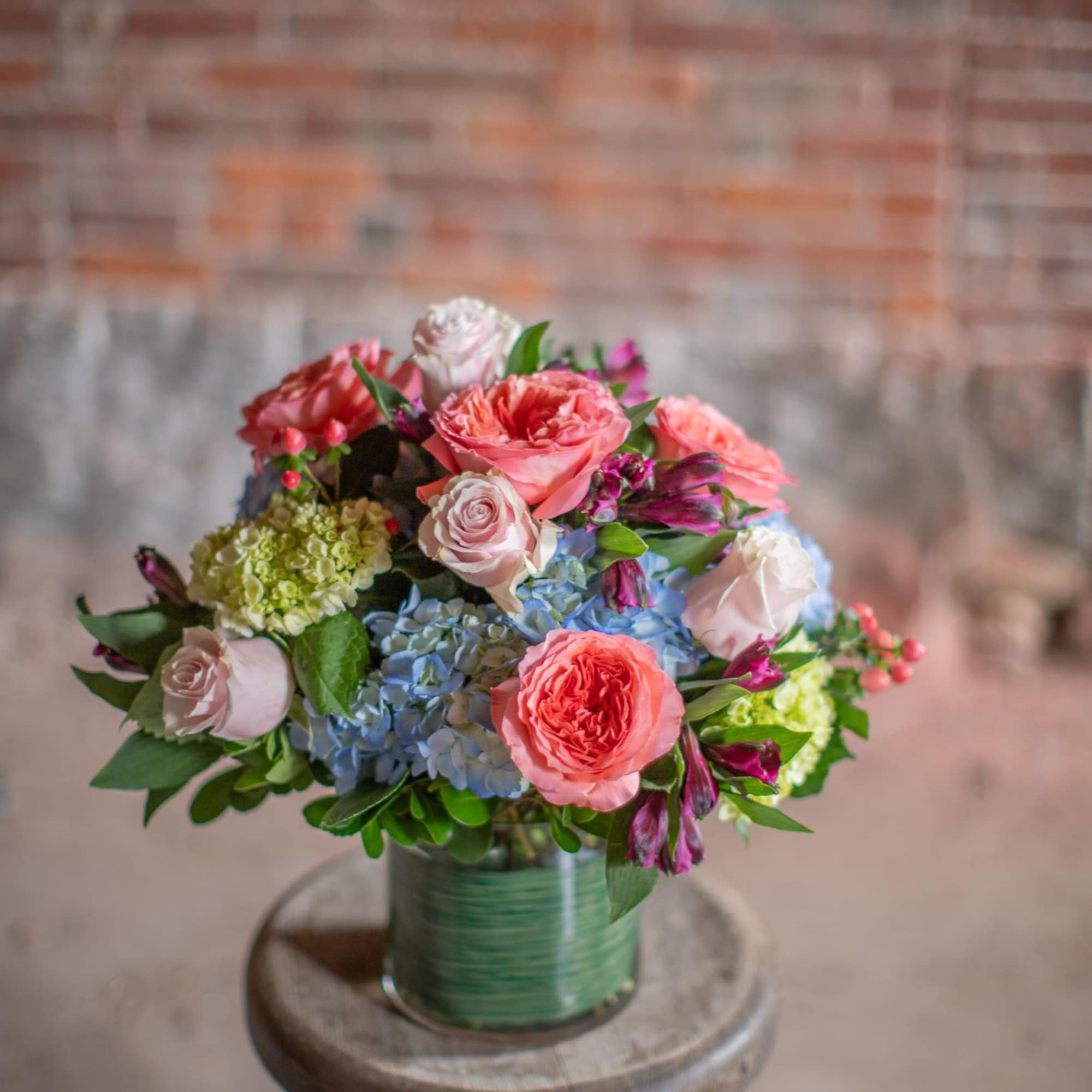 Mixed pink and blue flower bouquet in a green glass vase