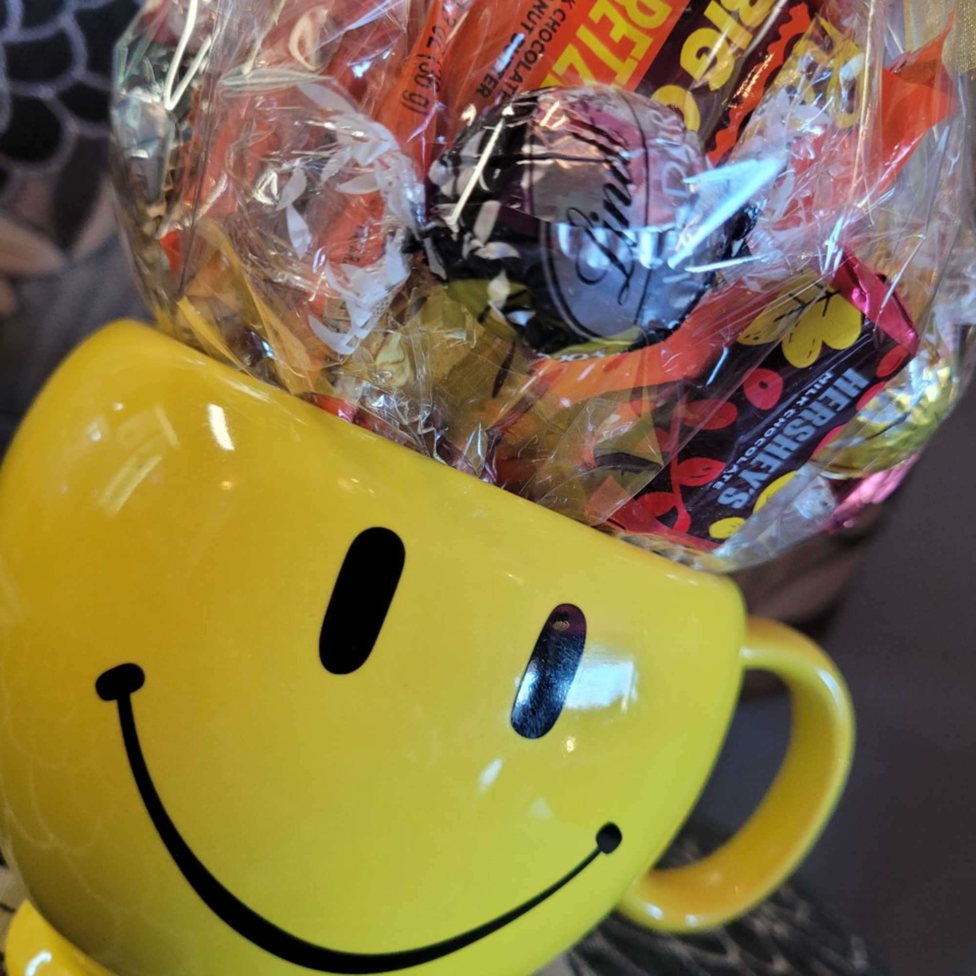 A mug with a foam based candy arrangement inside, wrapped in festive