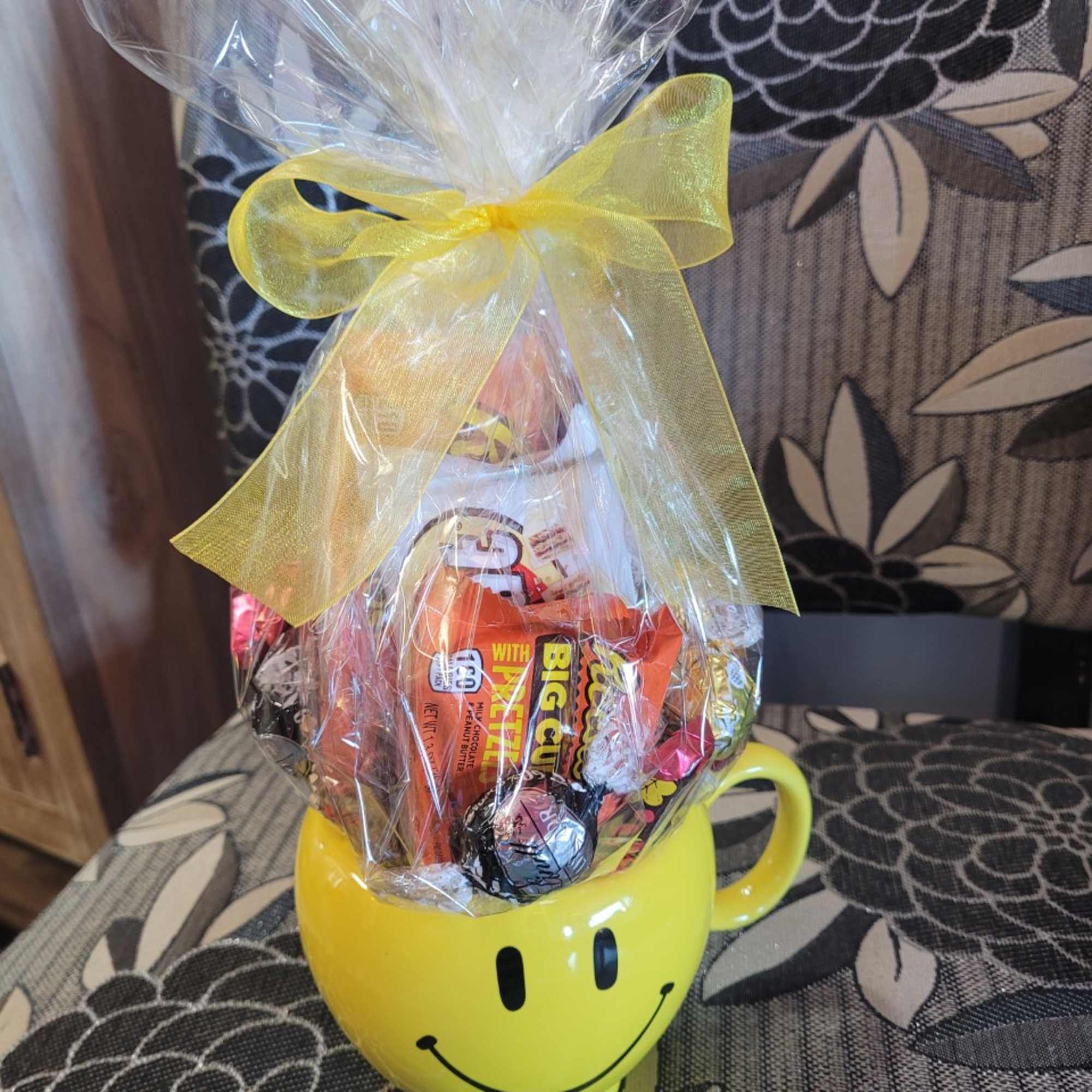 A mug with a foam based candy arrangement inside, wrapped in festive