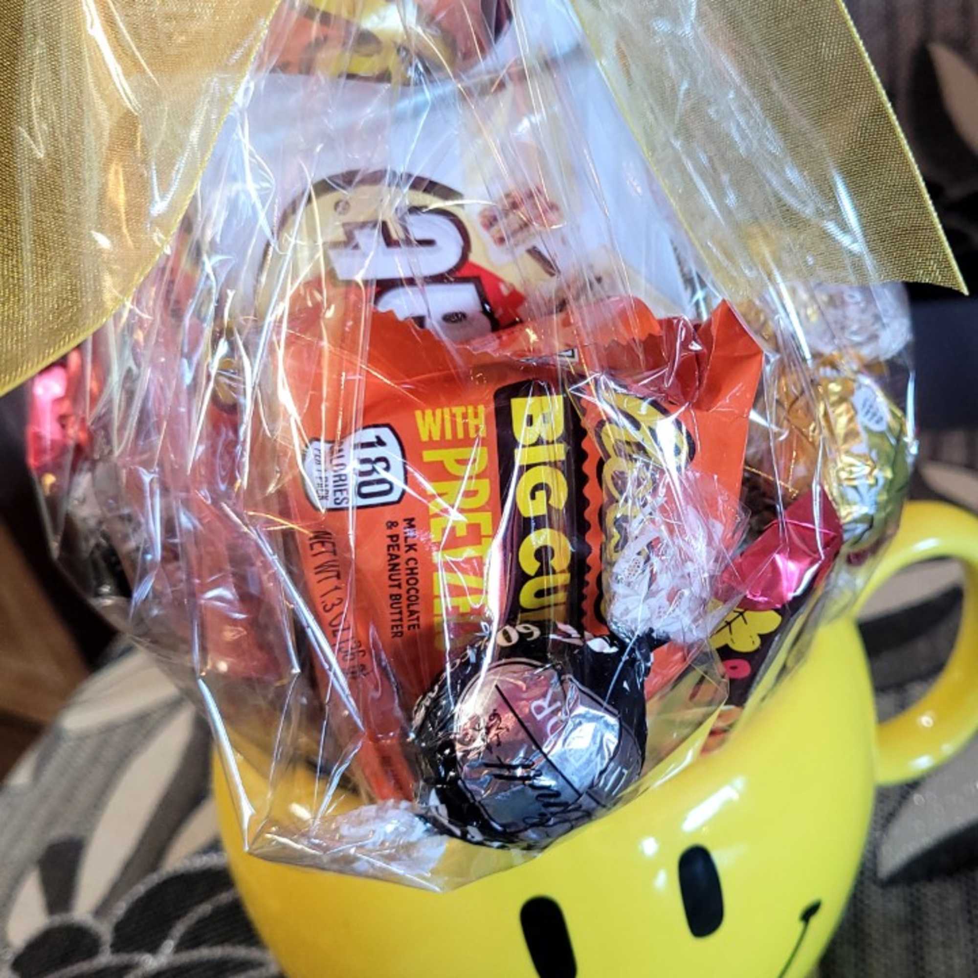 A mug with a foam based candy arrangement inside, wrapped in festive