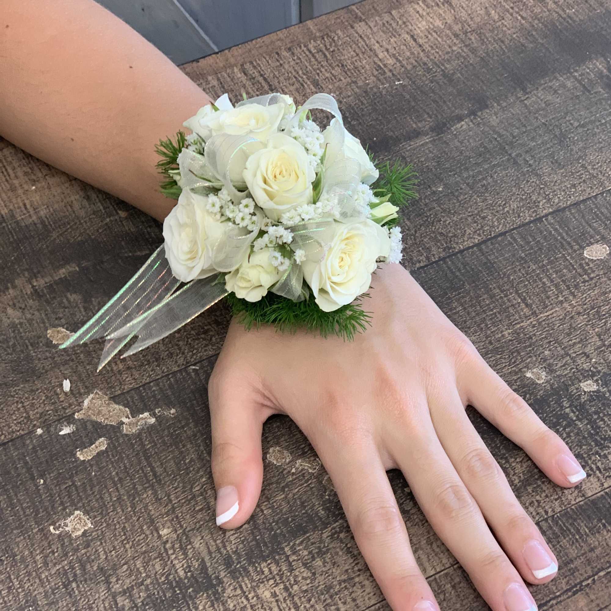 White rose wrist corsage with ribbon on a person's wrist