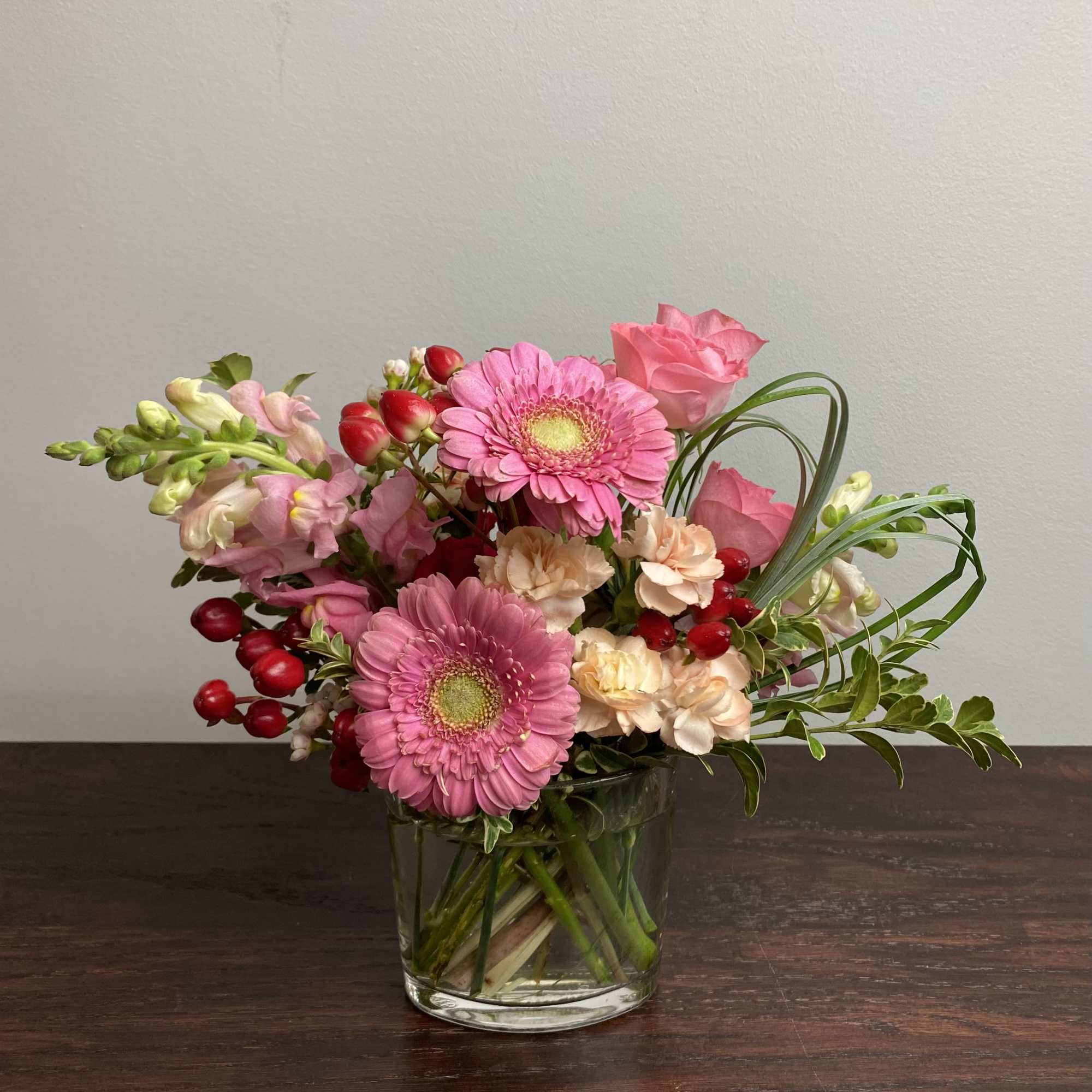 Pink gerbera daisies and roses in a clear glass vase
