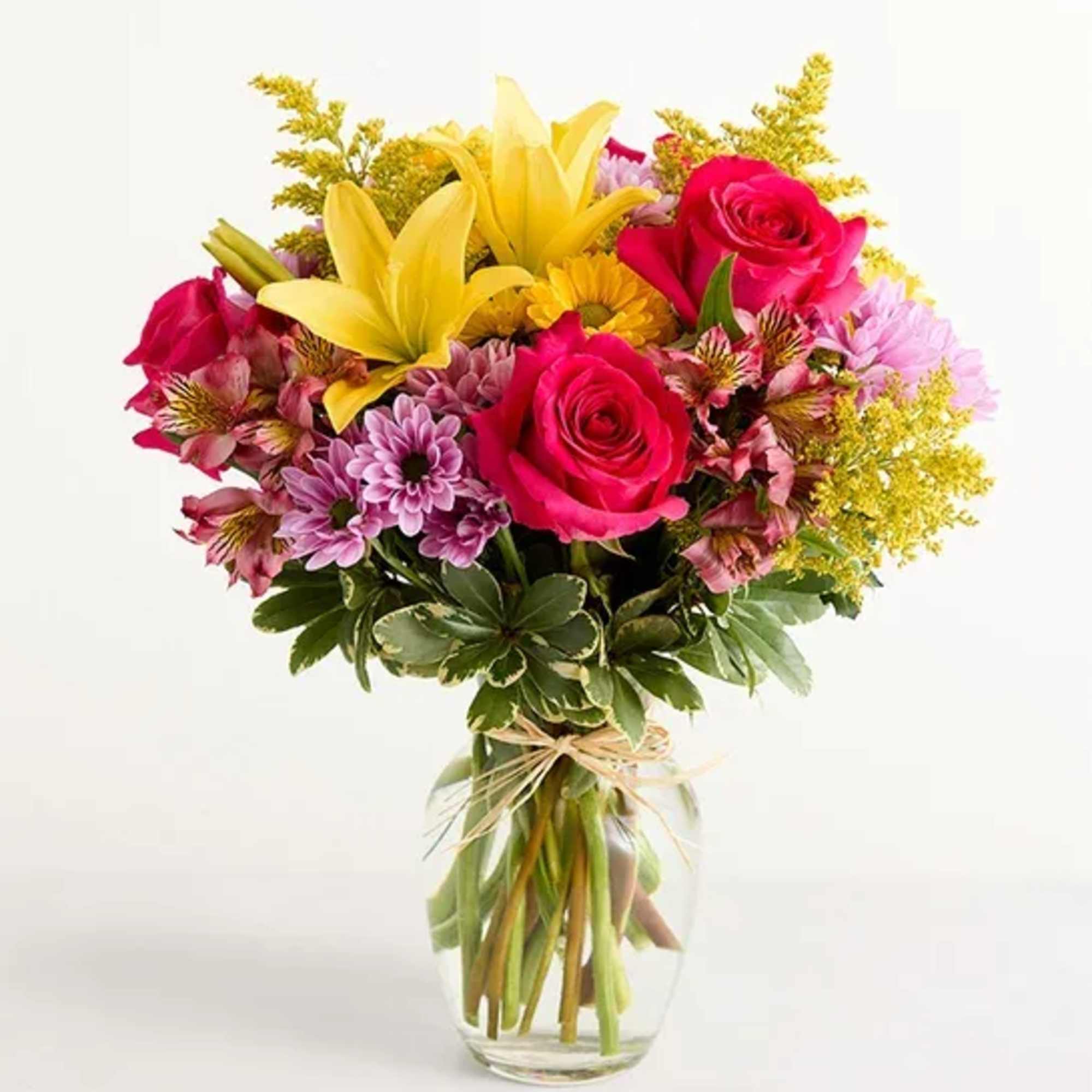 In a clear vase with yellow lilies, hot pink roses, lavender daisies