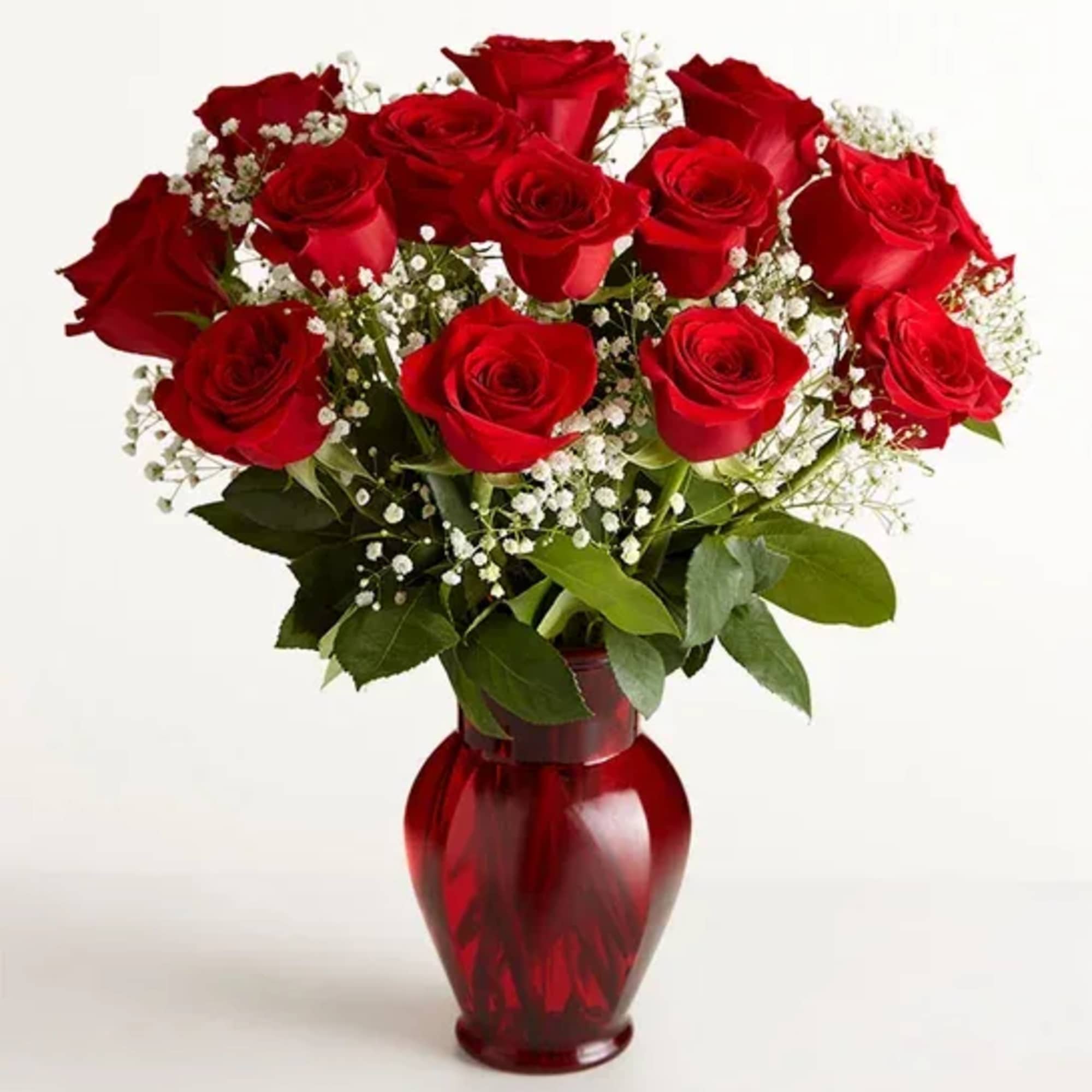 Red roses arranged in a red glass vase with white baby's breath