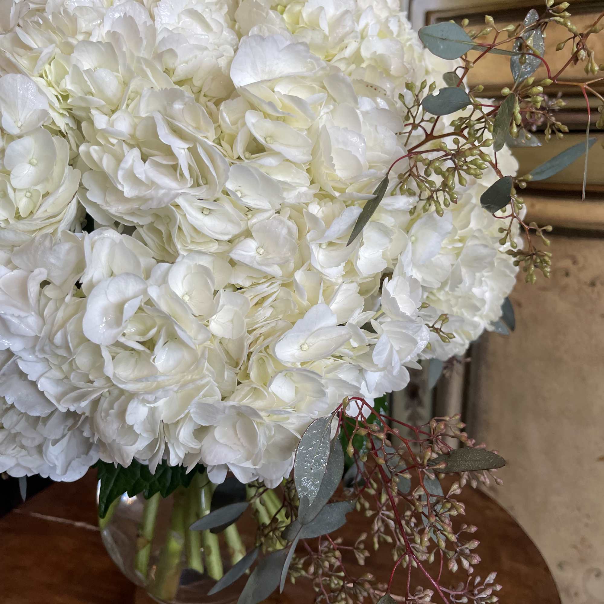 White hydrangea bouquet in a clear glass vase with eucalyptus accents