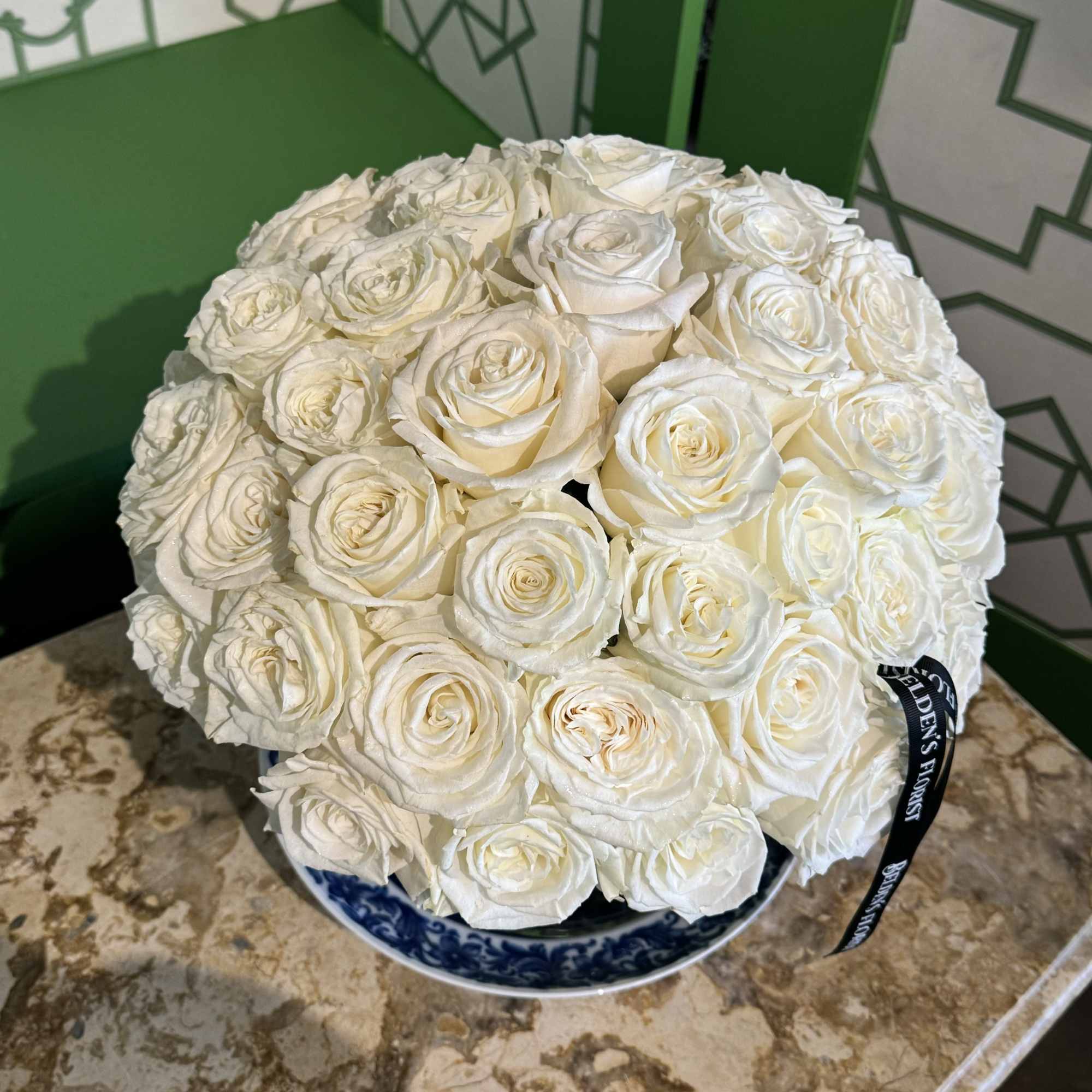 Round bouquet of white roses in a blue-and-white bowl