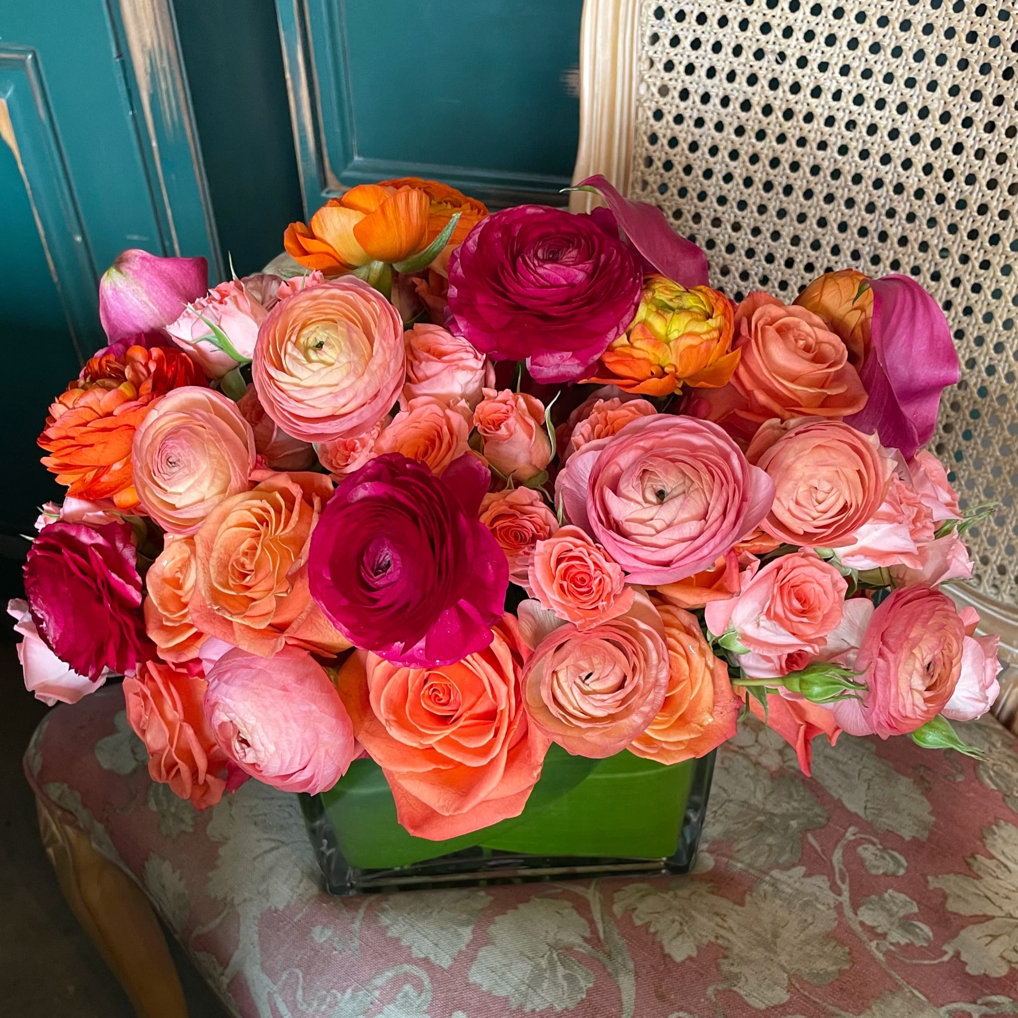 Mixed bouquet of pink, coral, orange, and magenta flowers in a green vase