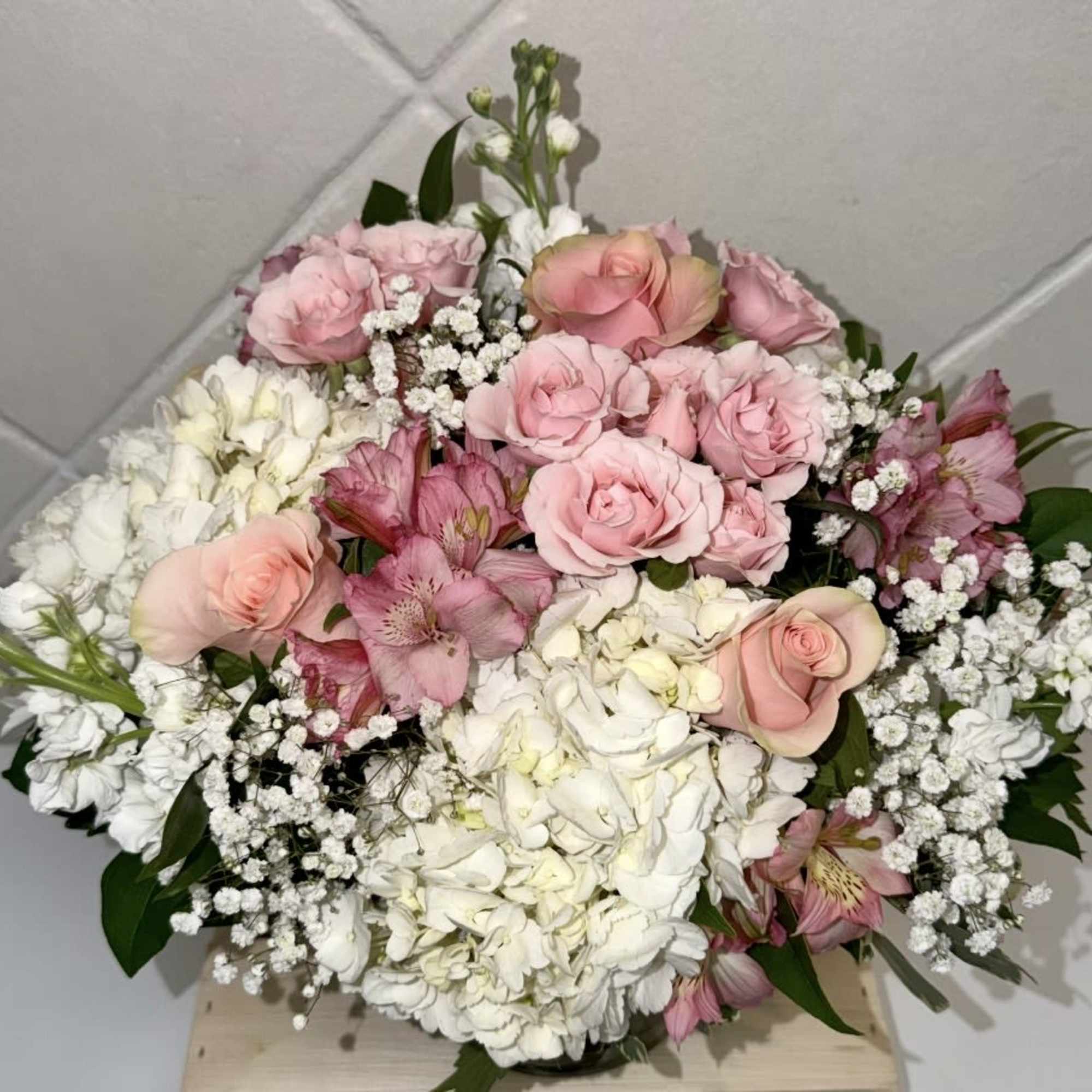 Clusters of pastels and pink roses mingle with large white hydrangea blooms