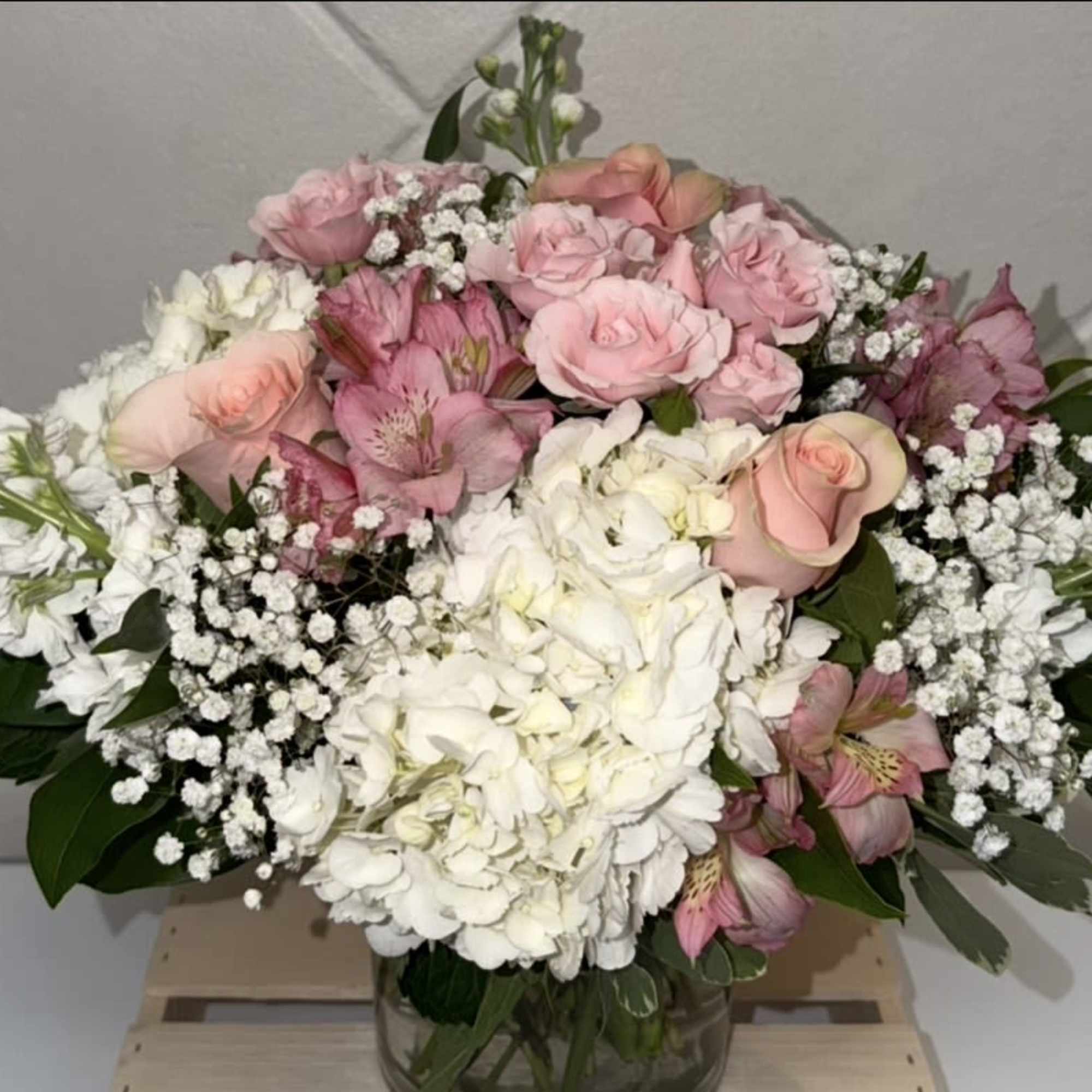 Clusters of pastels and pink roses mingle with large white hydrangea blooms