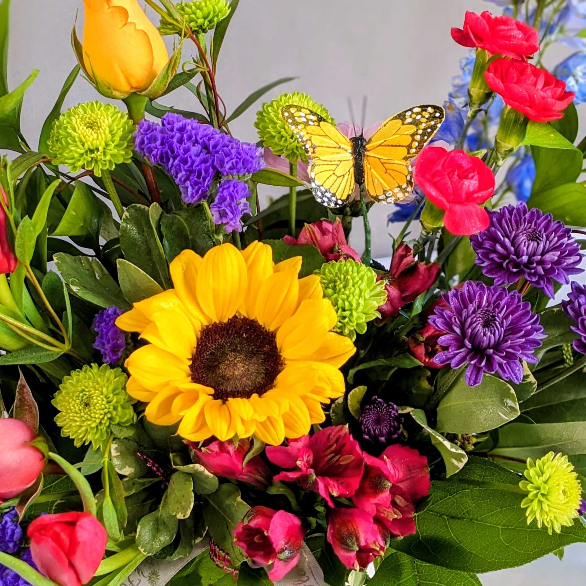 Colorful mixed bouquet with a sunflower, roses, and a butterfly pick