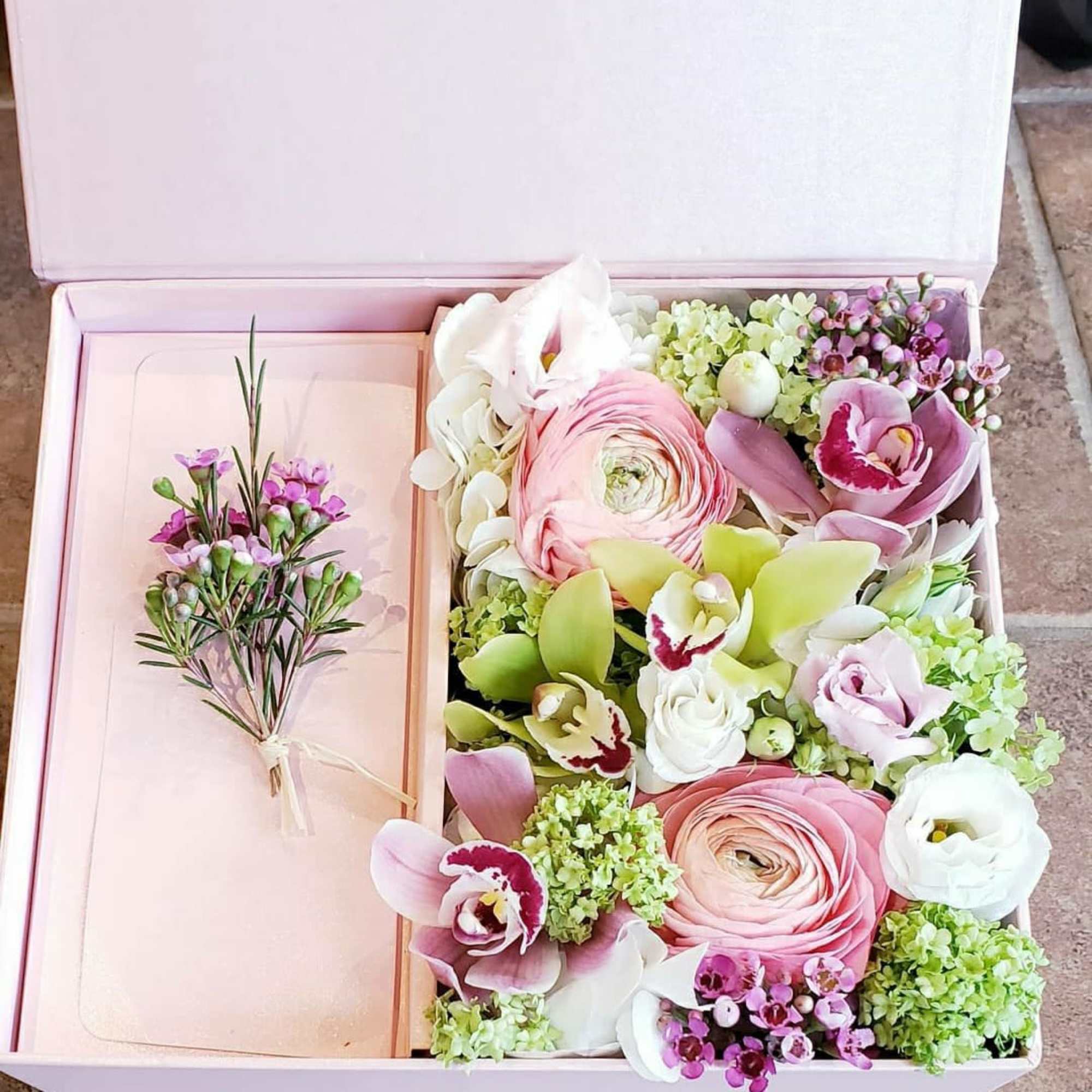 Pink gift box with assorted pastel flowers and a small boutonniere