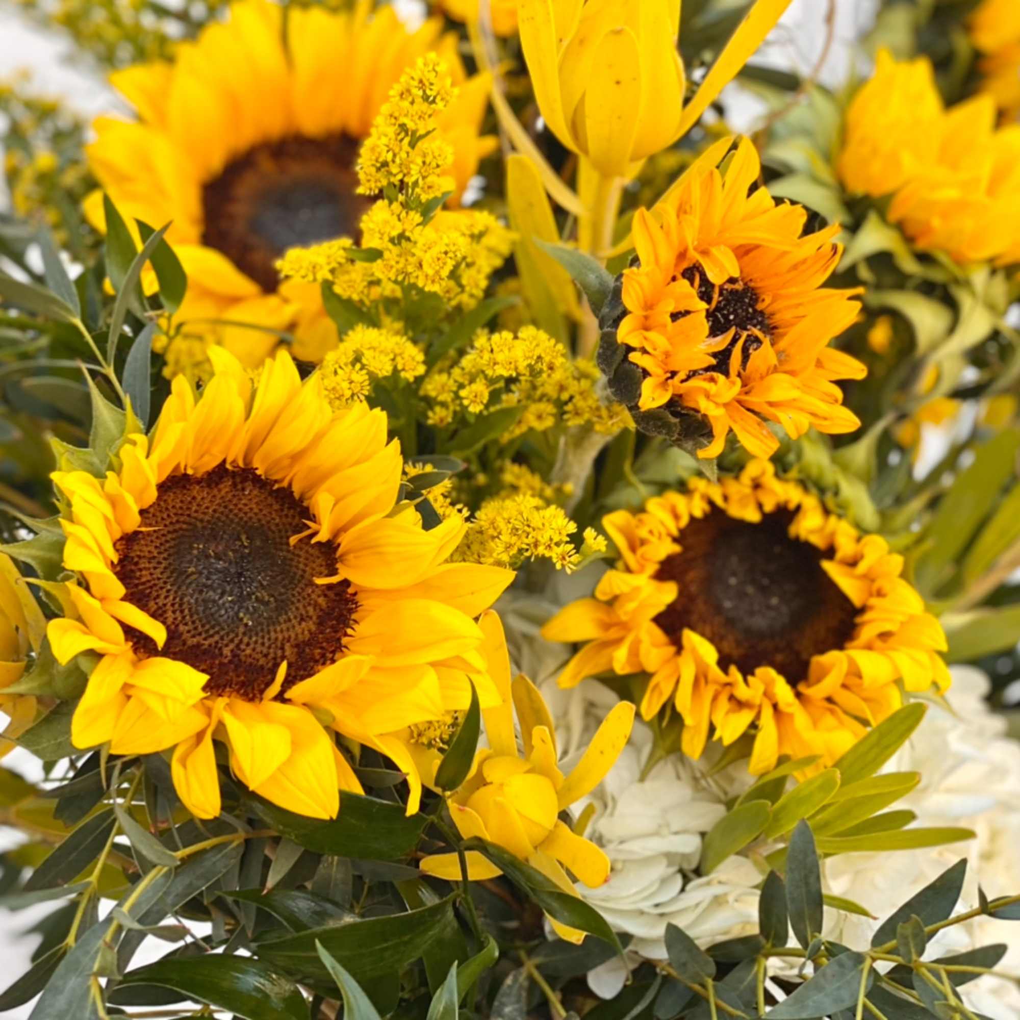 Bouquet of yellow sunflowers with white flowers and greenery