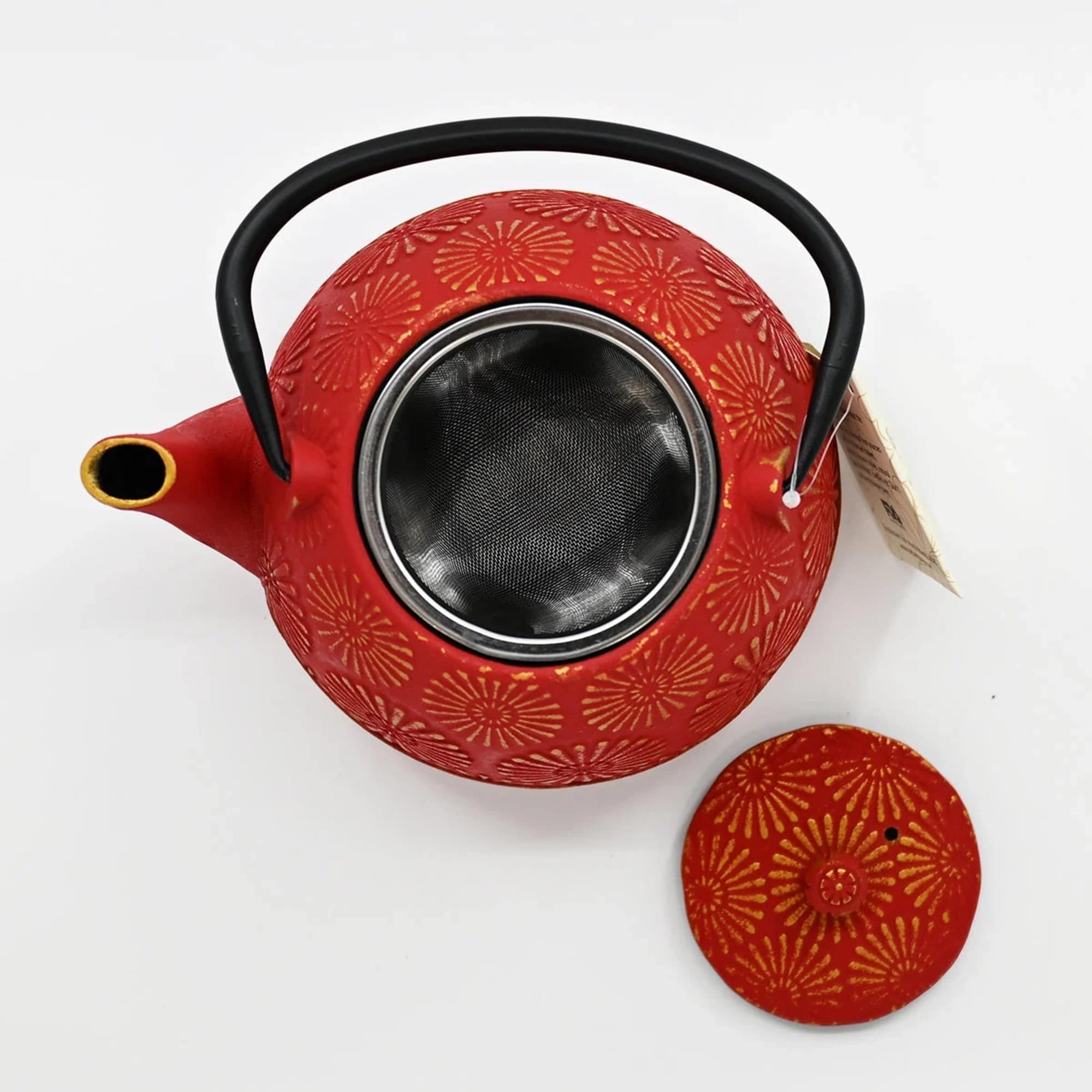 Red patterned teapot with a black handle and lid on a white background