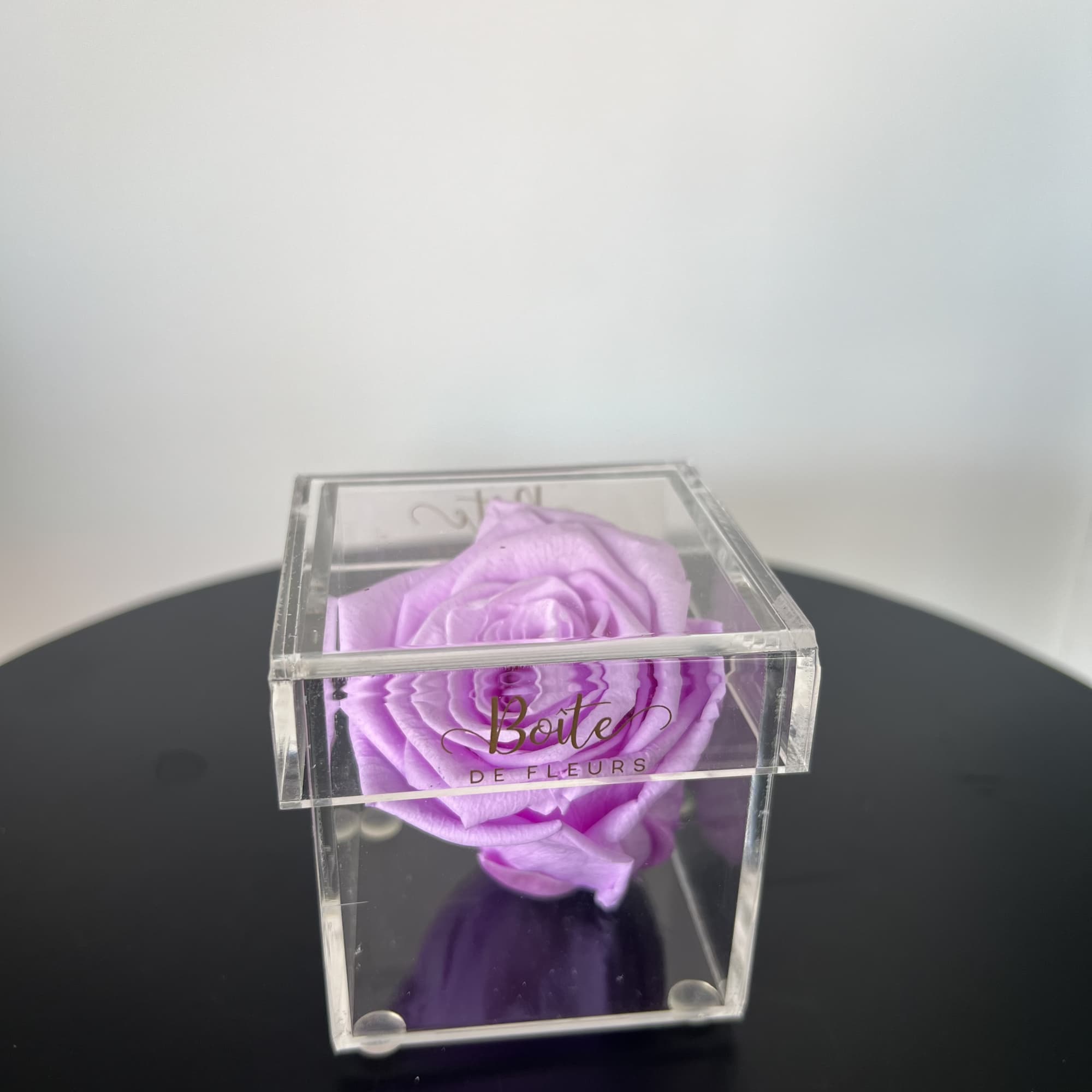 A single forever rose sits in a custom acrylic box. This petit