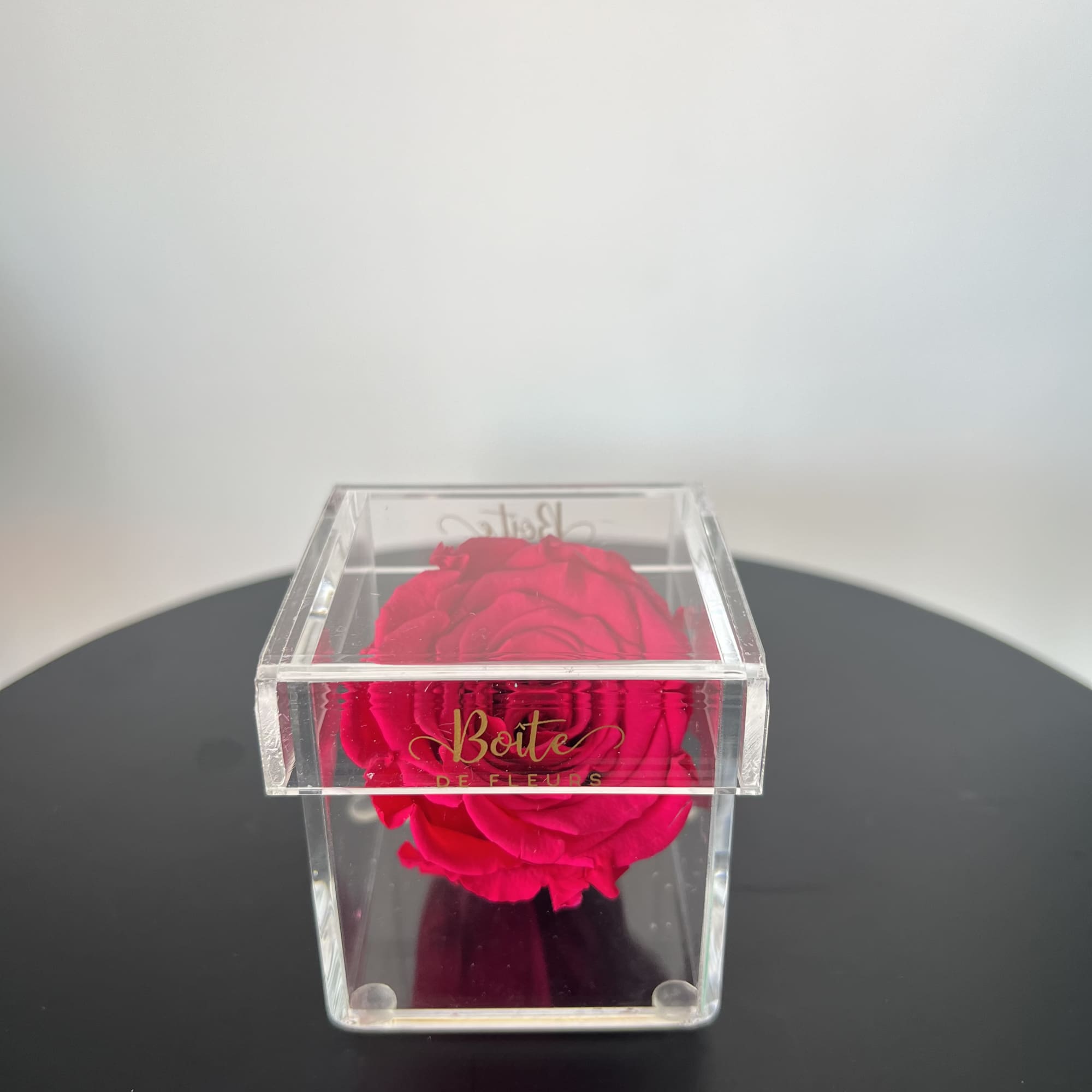 A single forever rose sits in a custom acrylic box. This petit