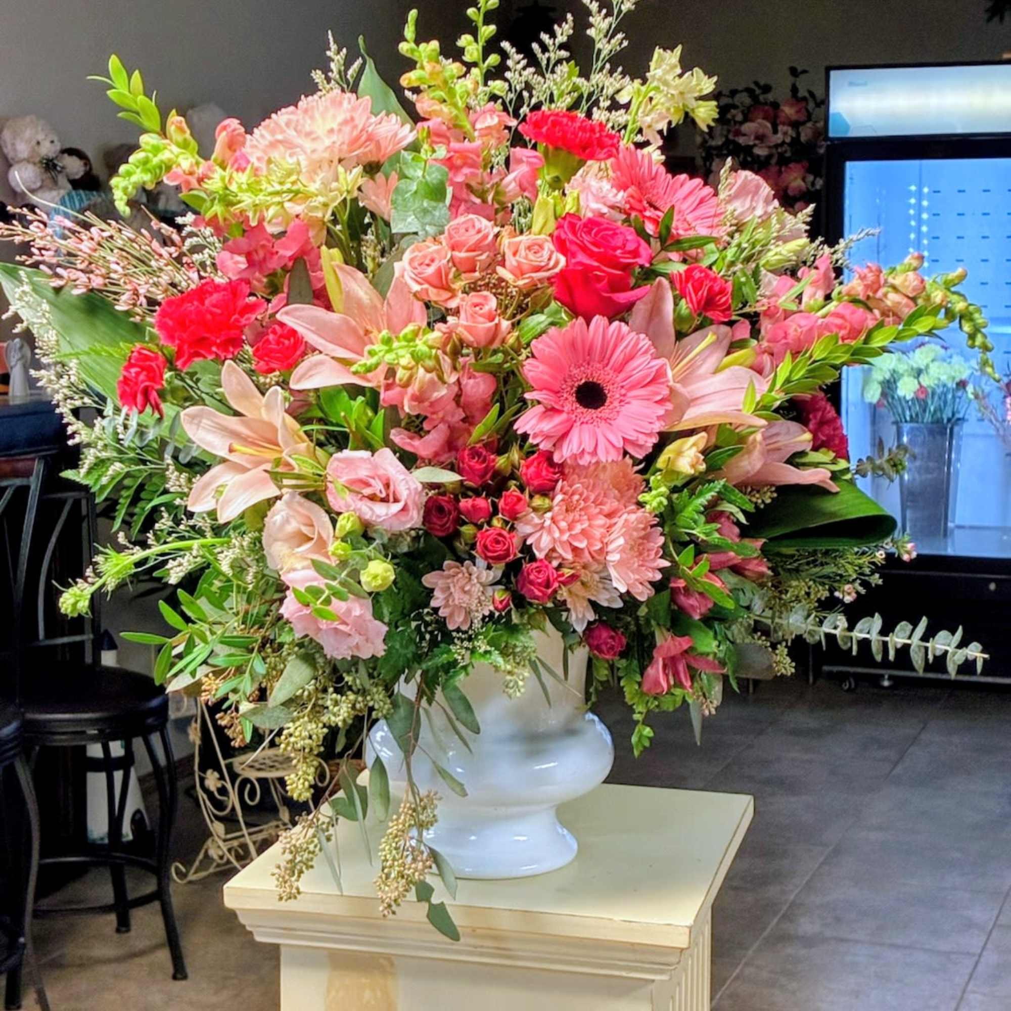 Large pink and peach floral arrangement in a white vase